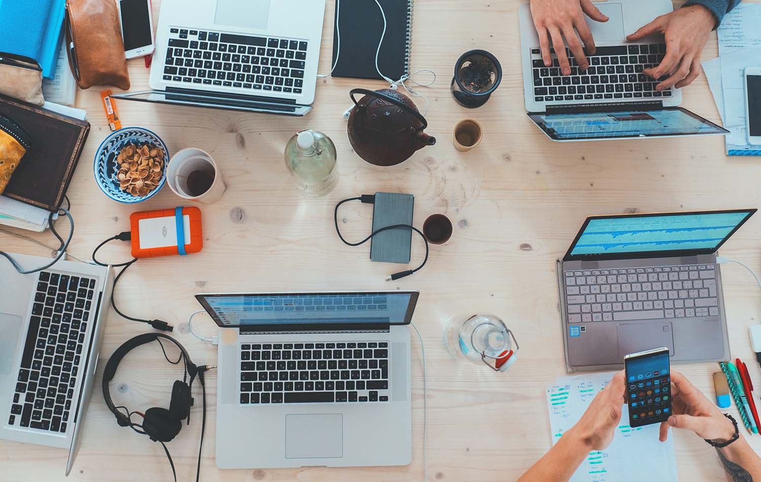 An arial view of a busy desk with multiple laptops and devices 