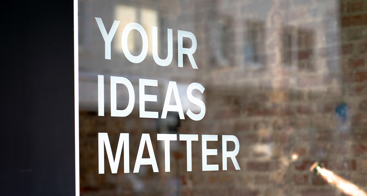 A sign on a glass door, reading 'Your ideas matter'