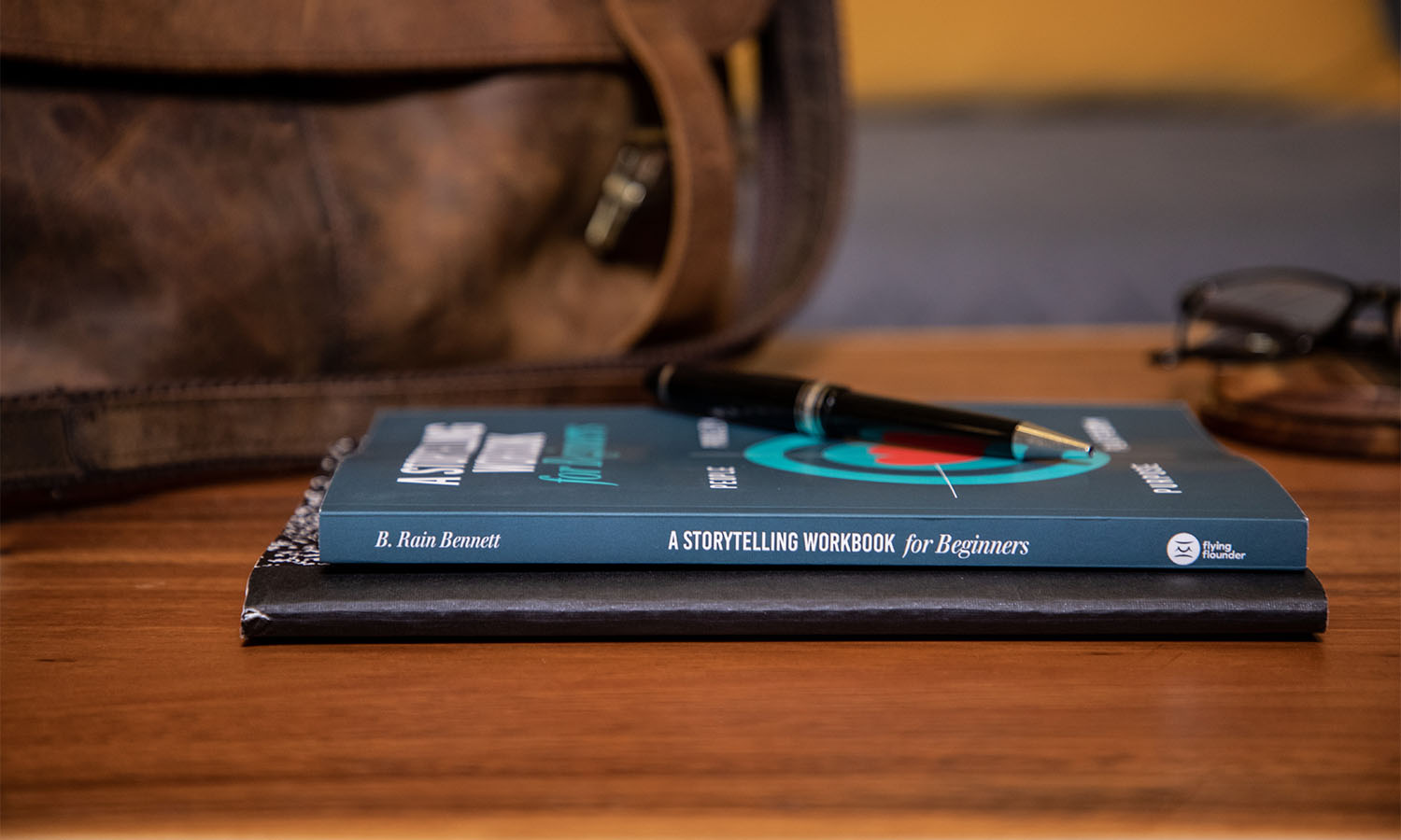 A desk with two books on, one of the books is called 'A storytelling workbook for beginners'.