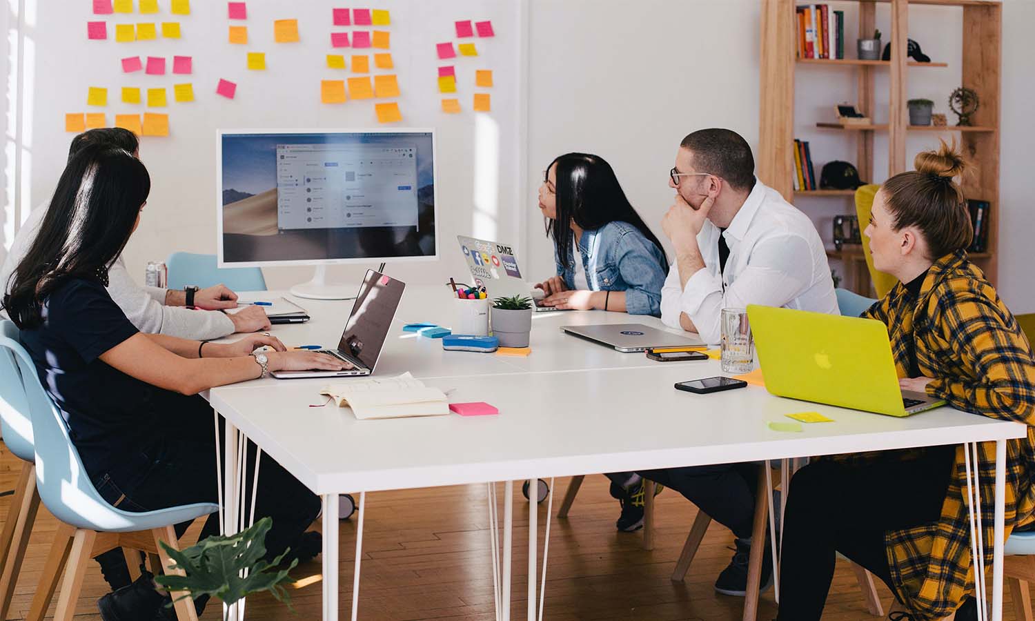 A group of office workers brainstorming ideas around a computer 