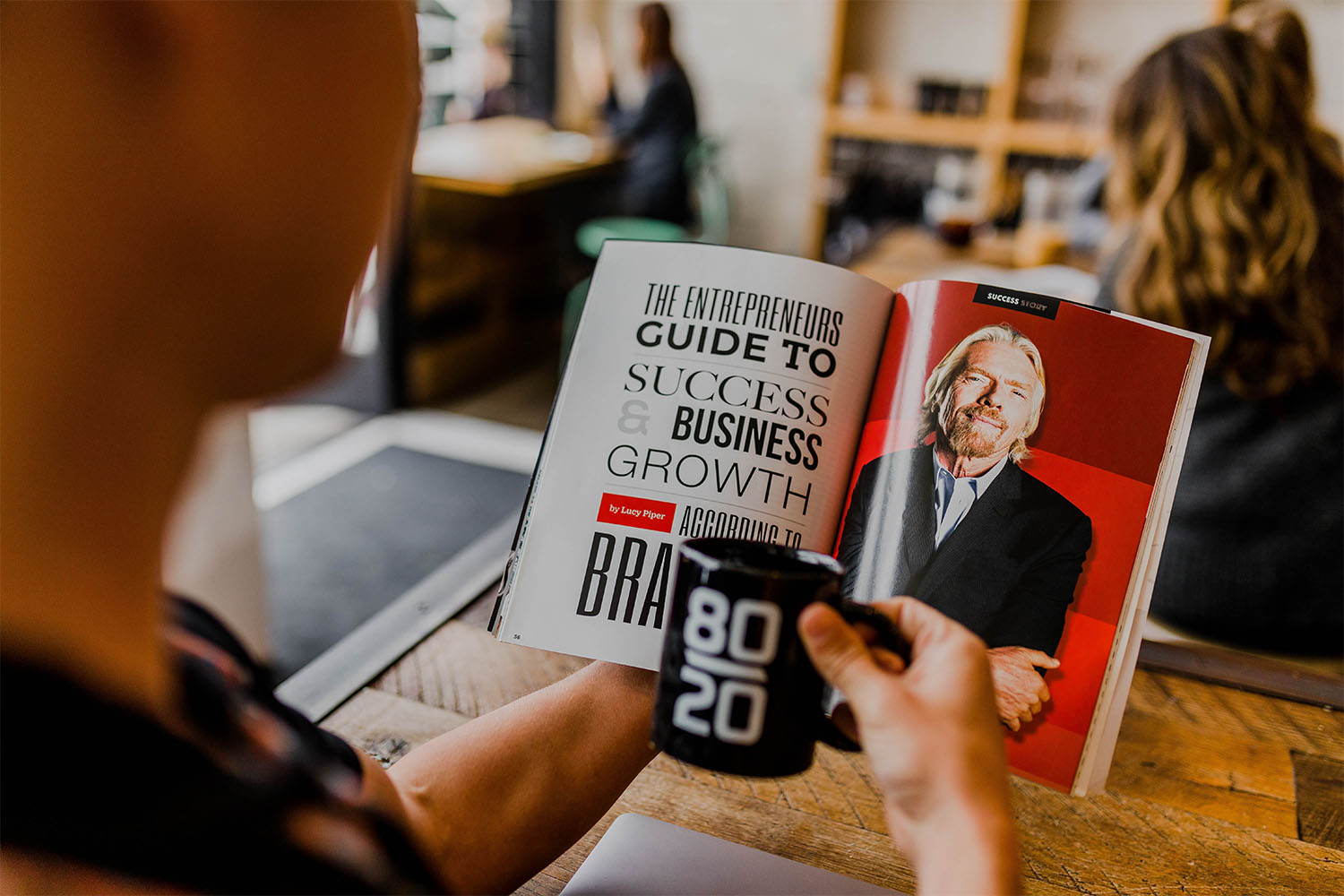 Someone reading a book about Richard Branson, the book is open on a page that reads 'The  entrepreneurs guide to success and business growth according to Richard Branson.