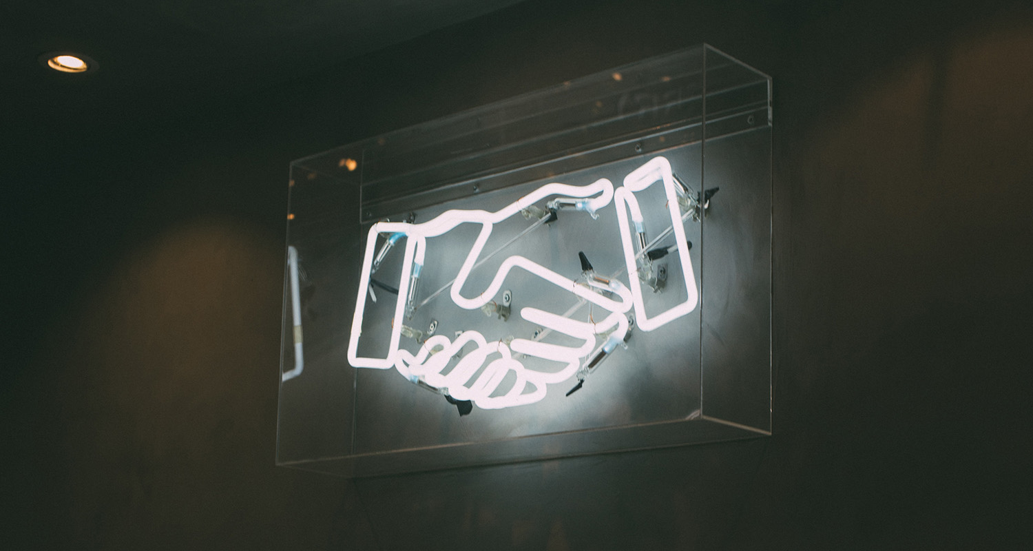 A neon lightbox showing two hands shaking