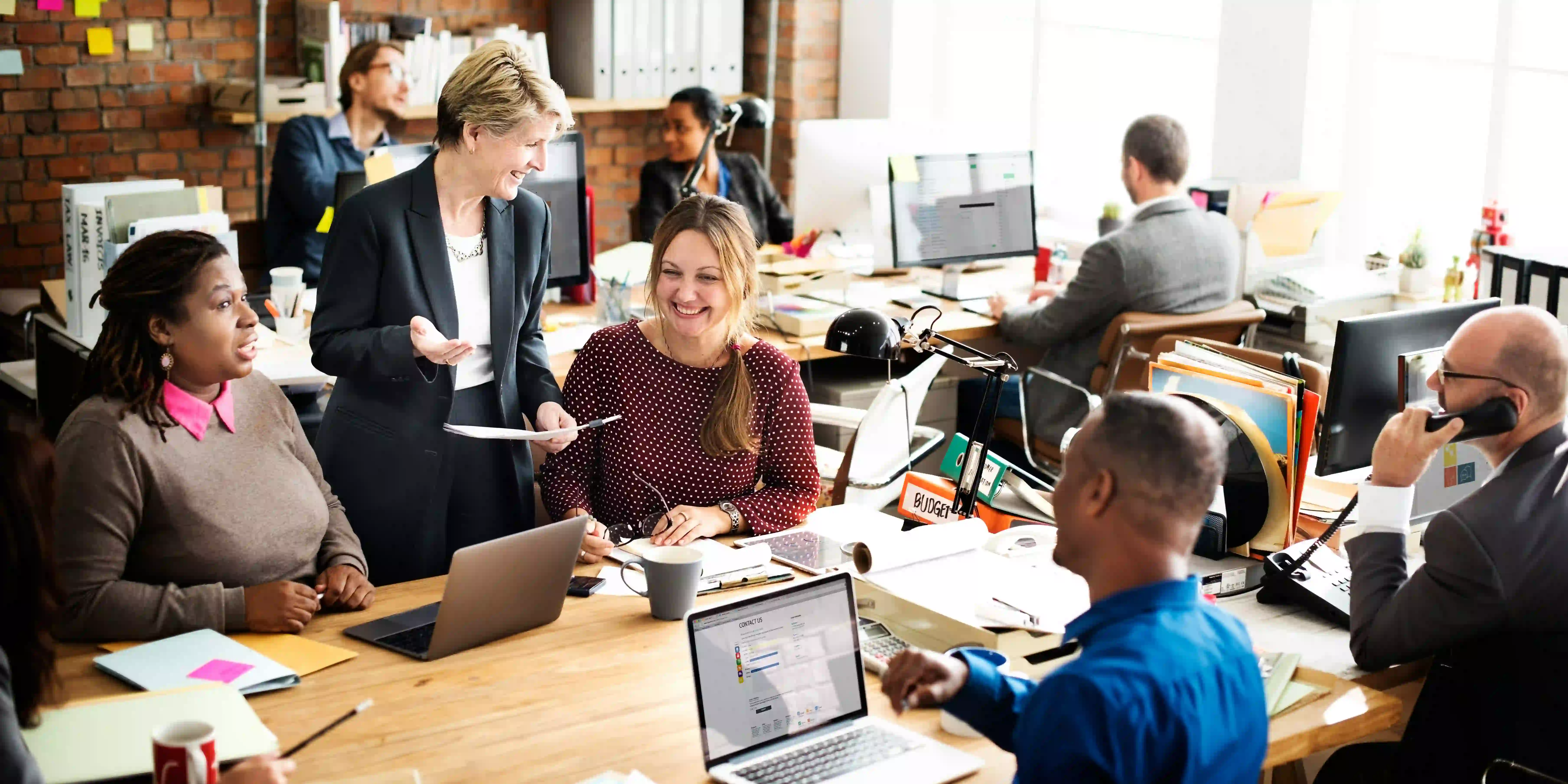 Many people with various functions sit in a bright office