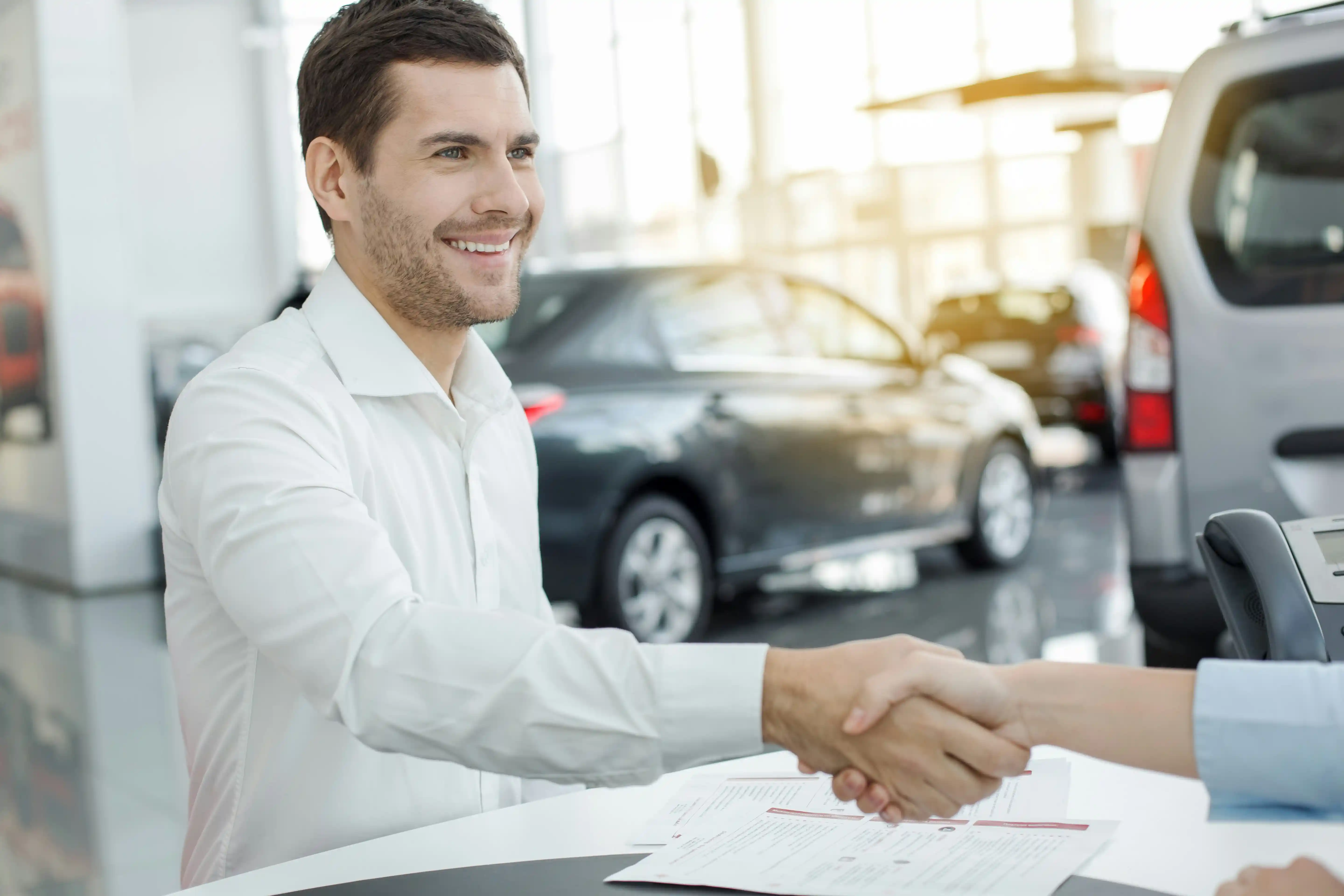A man in a white shirt shaking hands with a person.