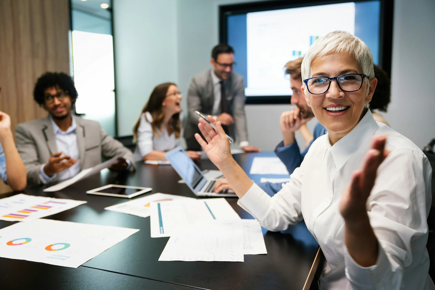 Several people talking at a meeting table. The photo was taken from the point of view of a participant sitting at the table.