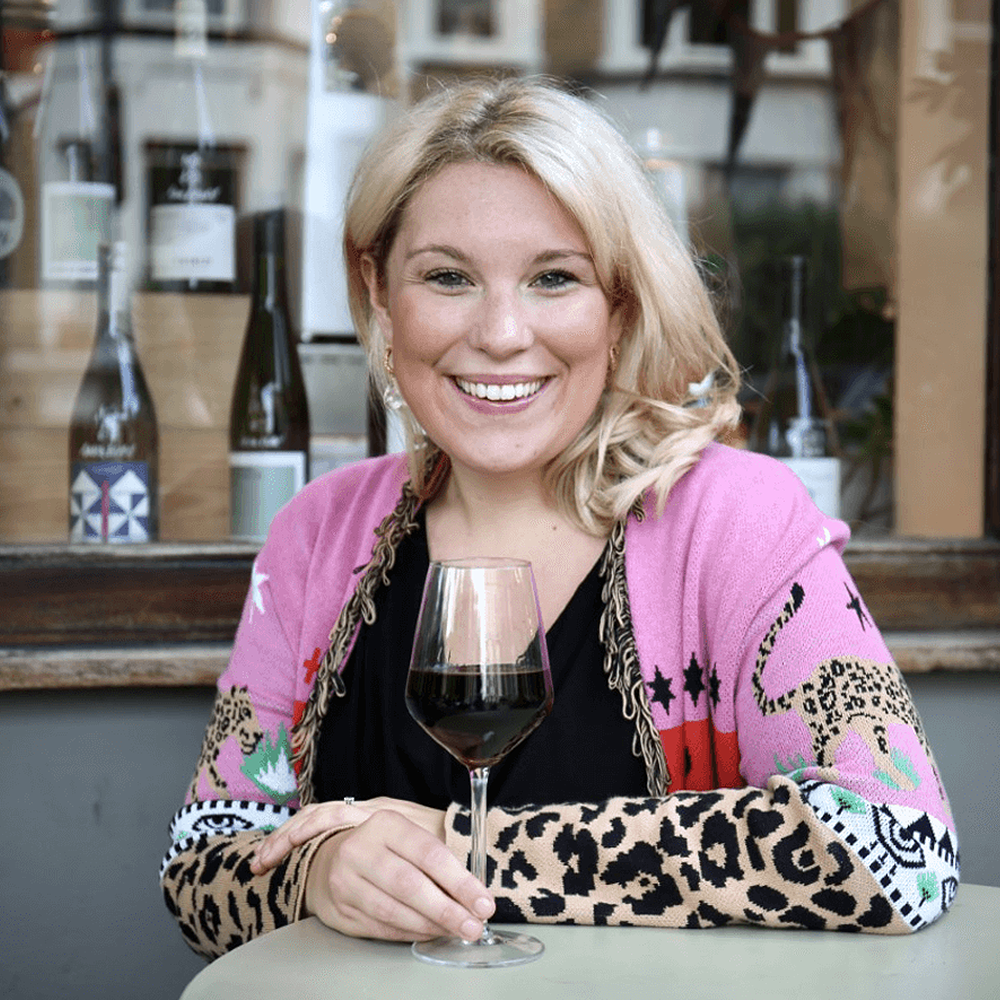 Laylo Founder: An image of a blonde women in a pink and cheetah jacket holding a glass of red wine. 