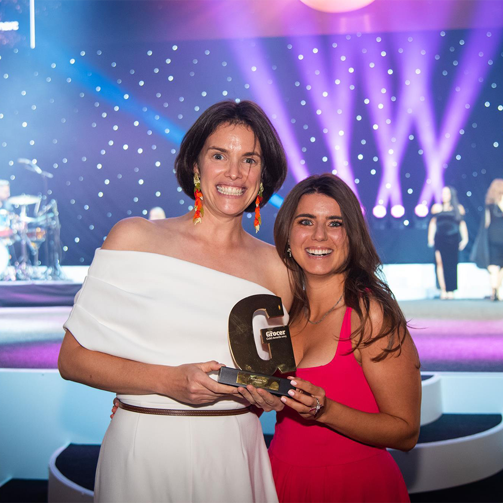 Founders of peachies looking at the camera, holding an award between them.