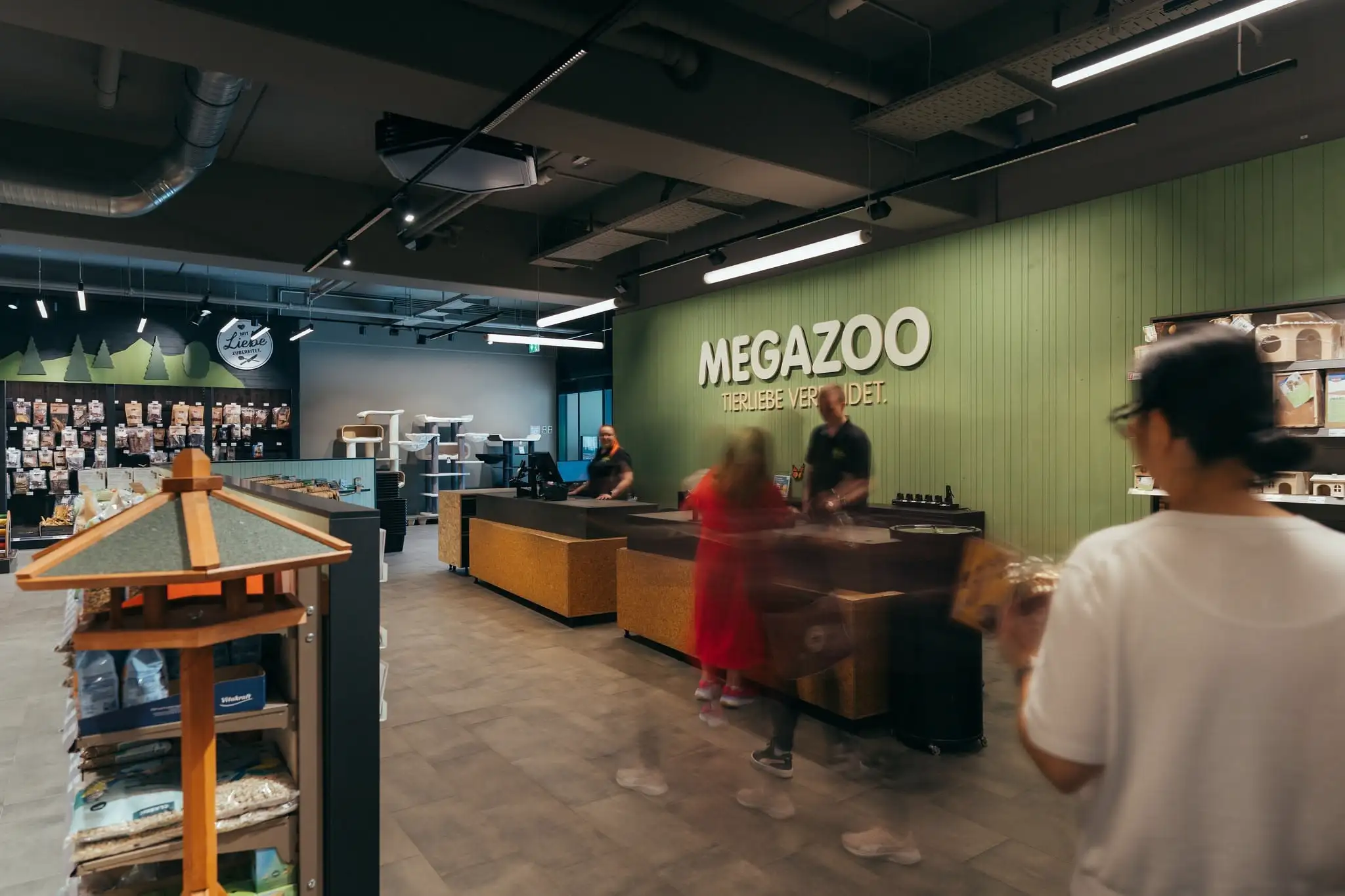 Interior of a Megazoo pet store showing customers approaching the checkout counters with two employees behind the counters.