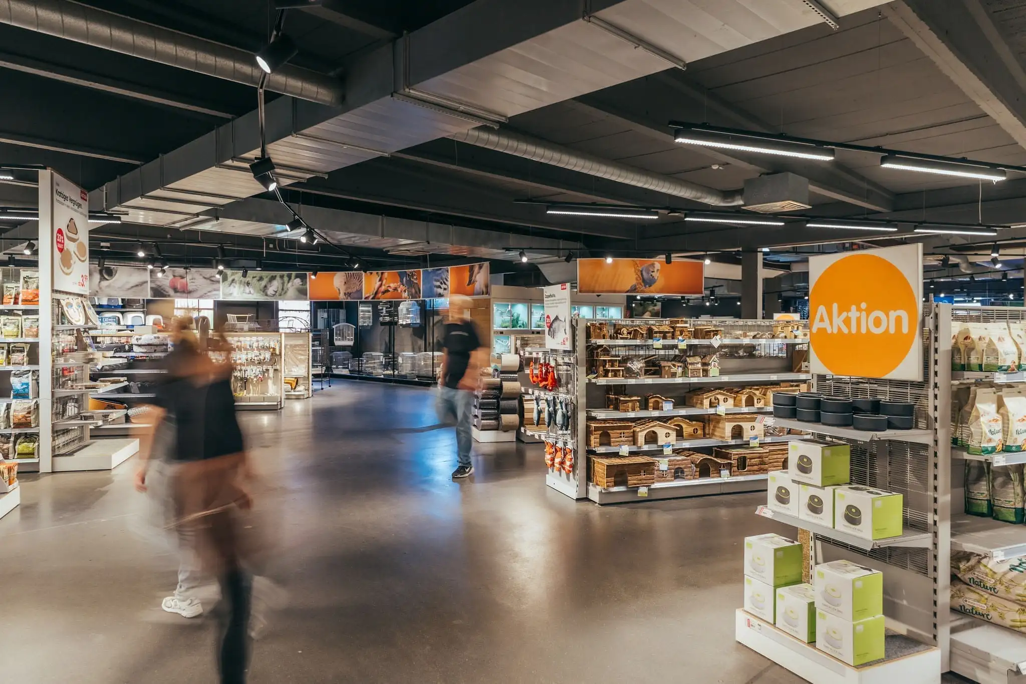 Interior of a pet store featuring shelves with pet houses, products, and a sign with 'Aktion' advertising a sale.