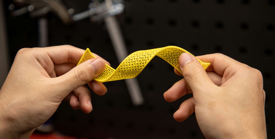 A close-up of a person twisting and testing a 3D printed material.