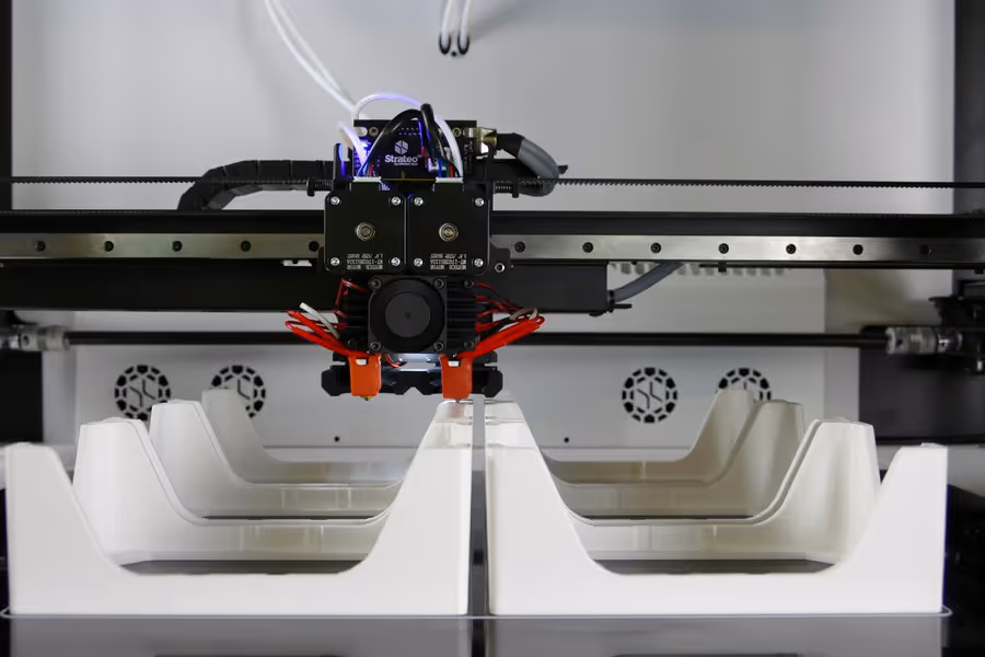 An industrial 3D printer in operation, producing multiple items of stock at once.