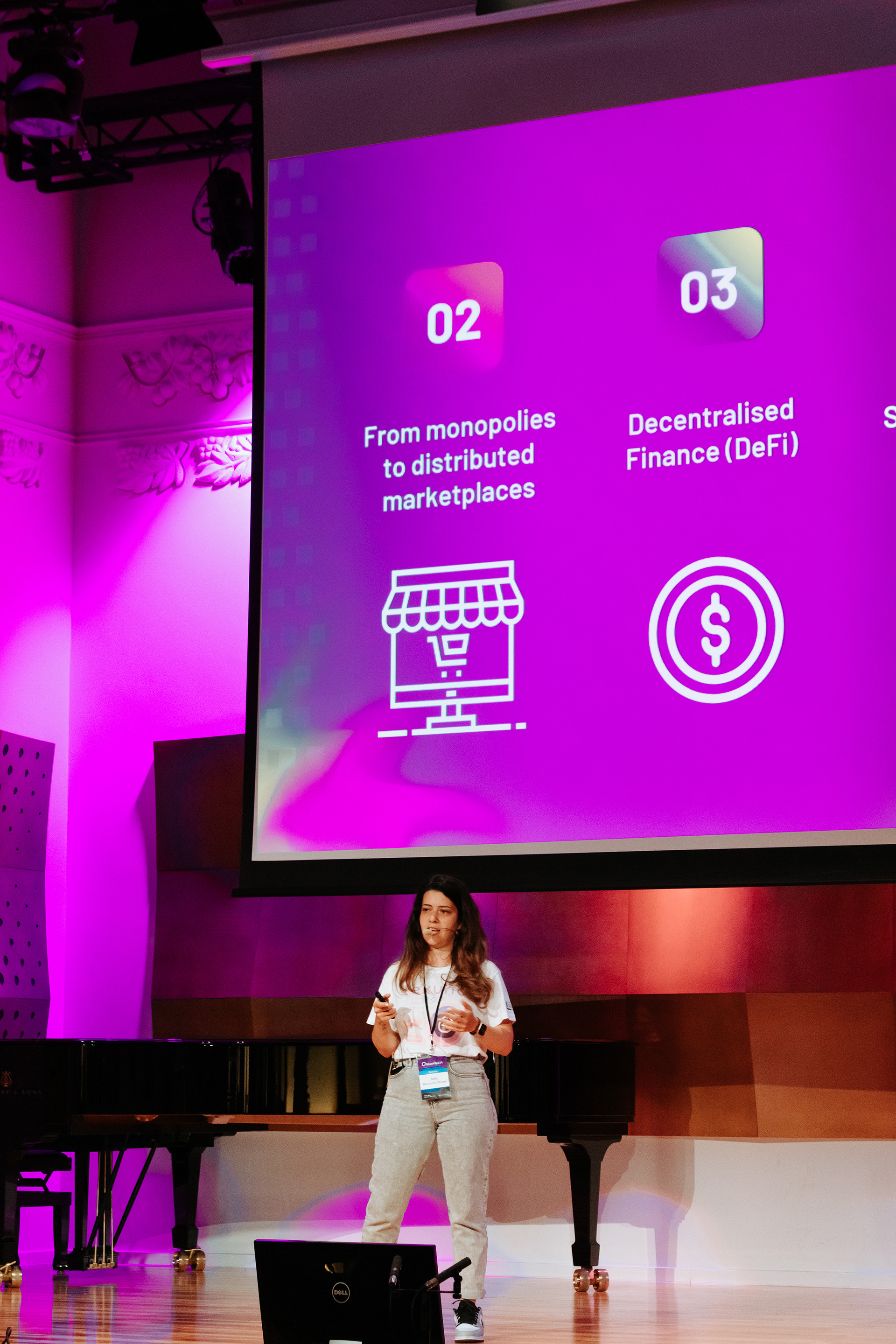 A woman is presenting a slide deck and talking on stage