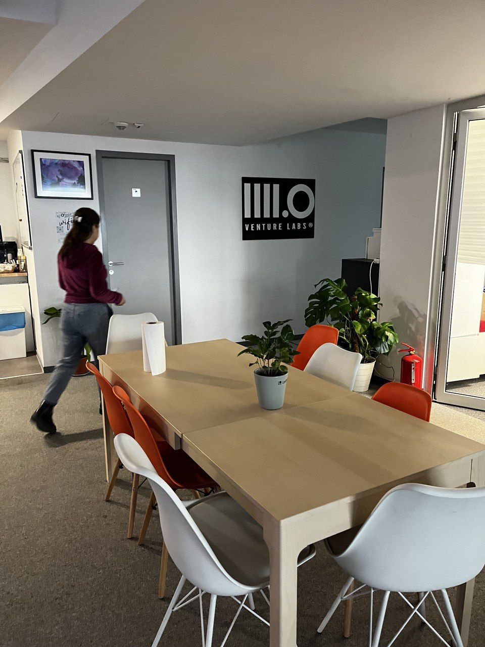 A woman is walking through an office, the 4 point O logo sits on one of the walls.