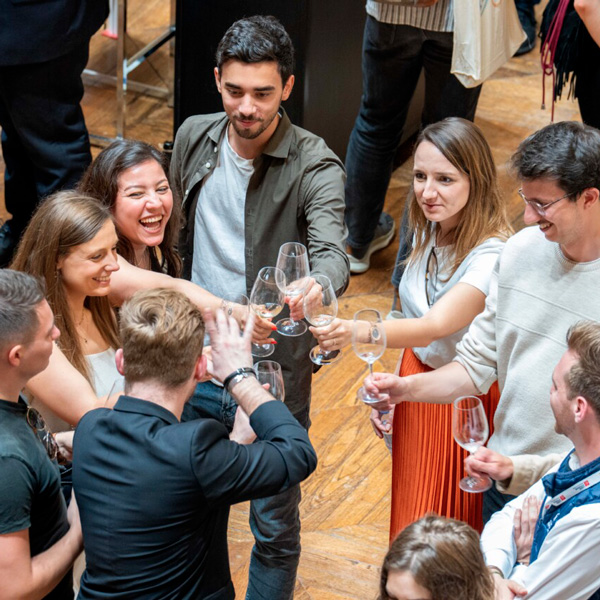 Group of young adults cheerfully toasting with wine glasses at a public tasting event.