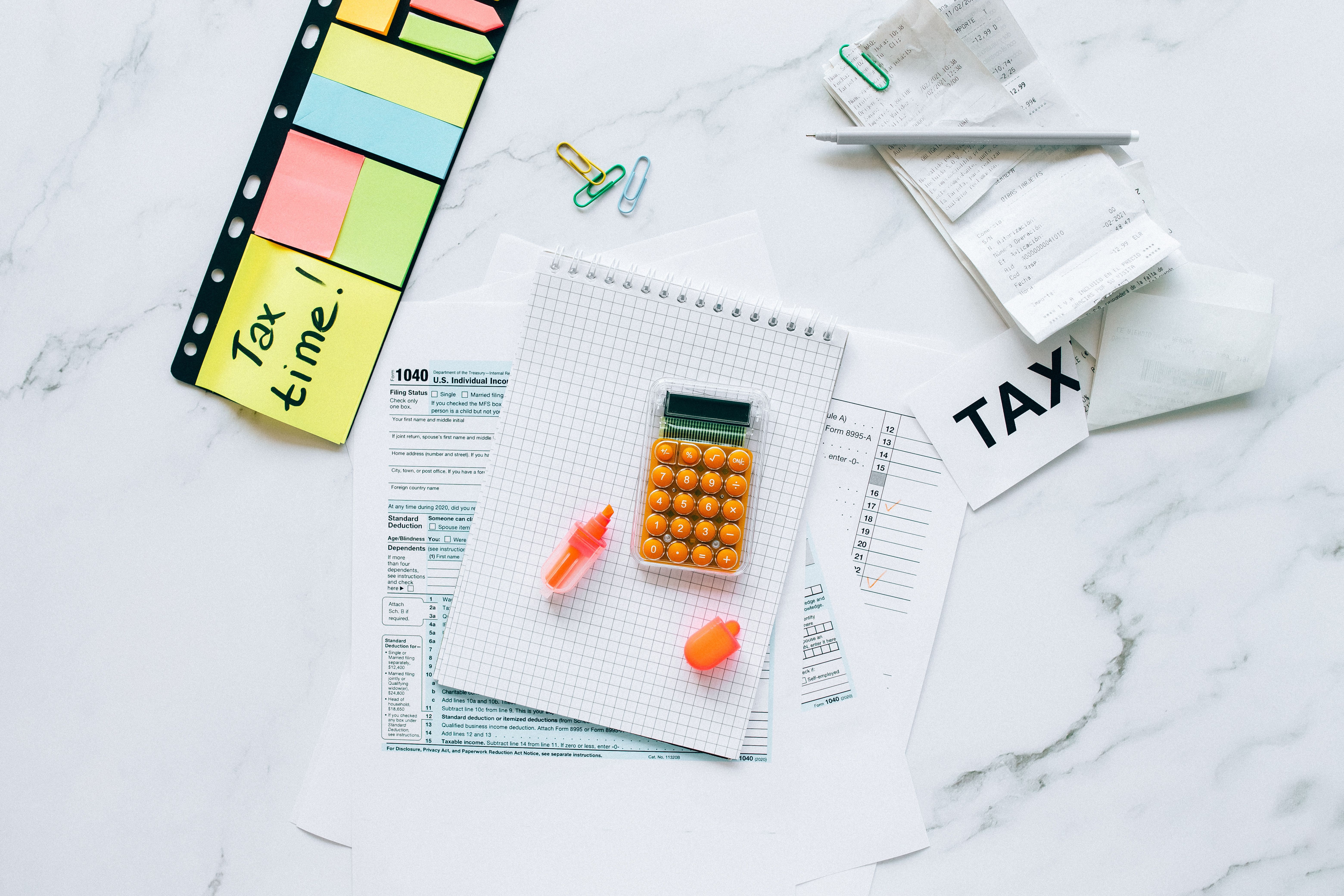 Calculatrice, carnet, notes adhésives et reçus sur un bureau, préparation de fin d'année pour maîtriser sa fiscalité