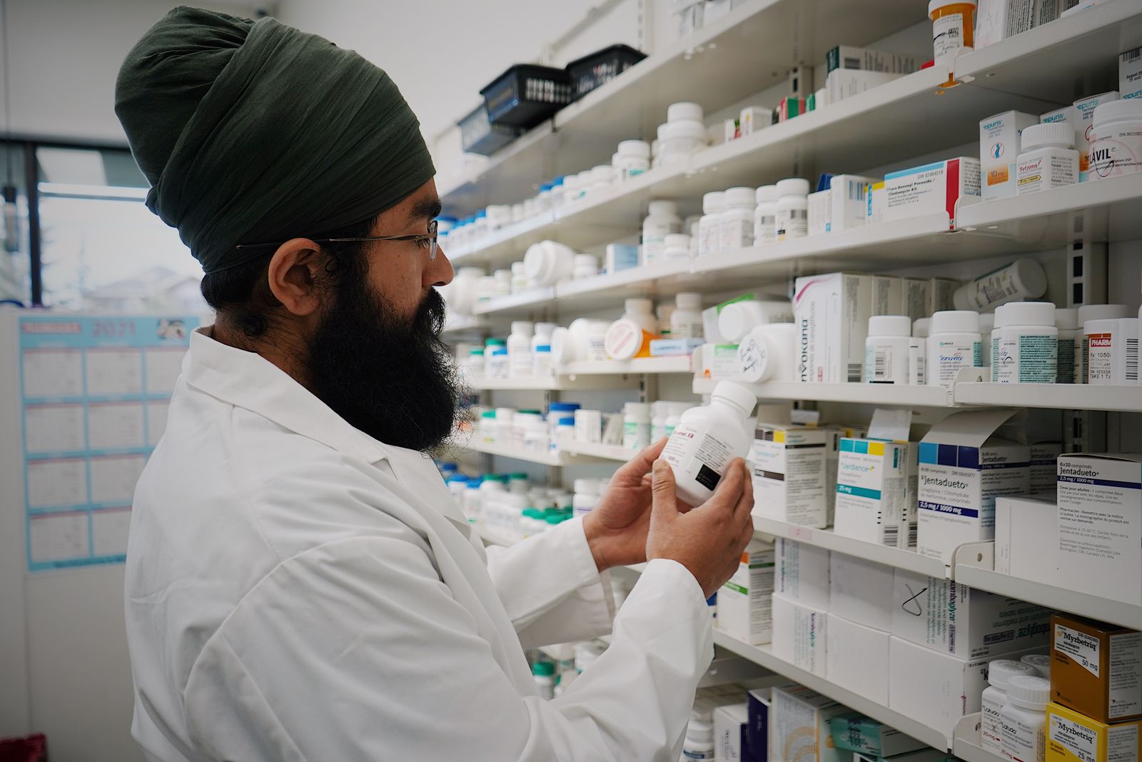 Pharmacien titulaire dans son officine devant les rayonnages, illustration de la cession d'une pharmacie