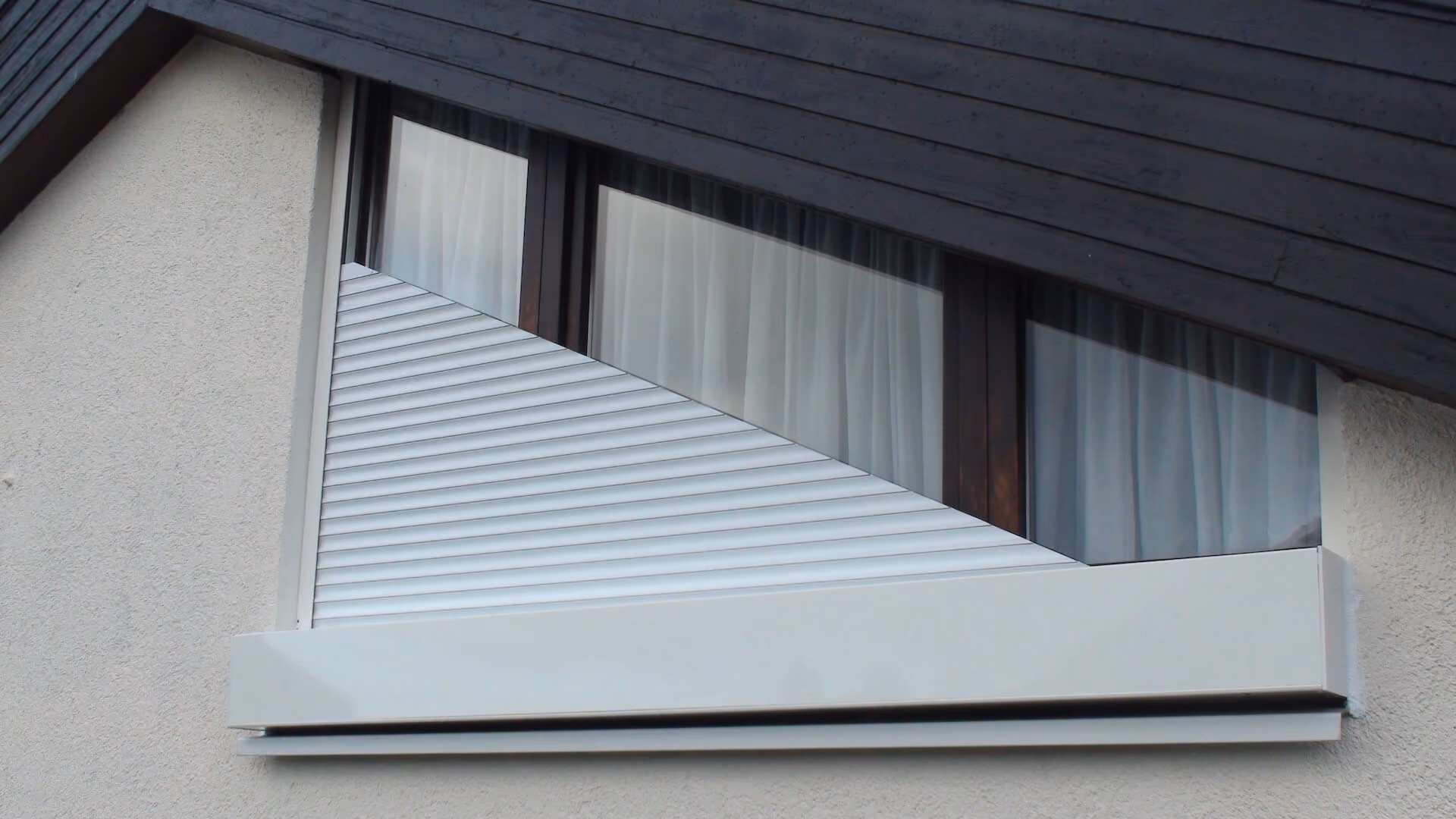 Weißer MULDIS-Rollladen an einem dreieckigen Giebelfenster.