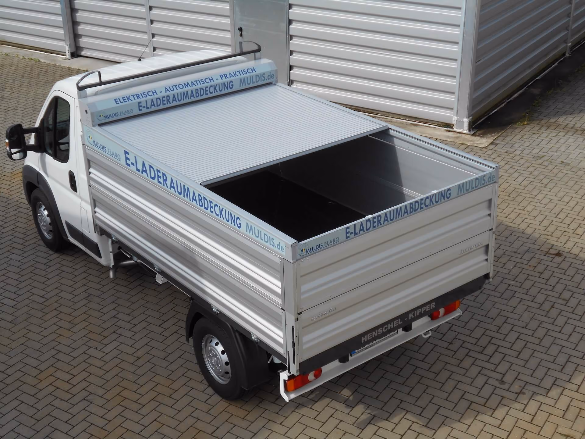 Transportfahrzeug mit offener Ladefläche und integrierter Rollladenabdeckung.