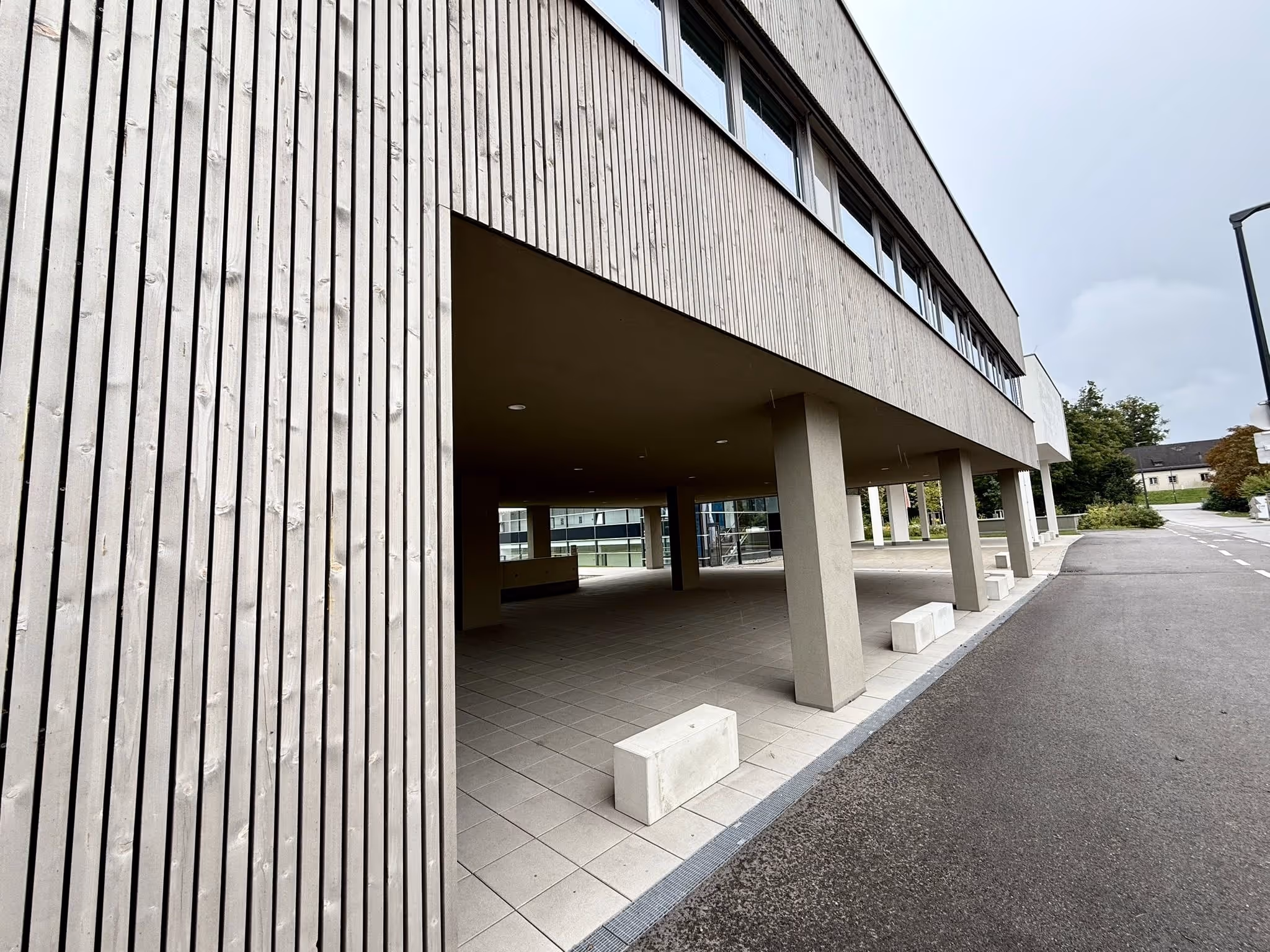 Holzfassade und offenes Erdgeschoss mit Parkmöglichkeiten