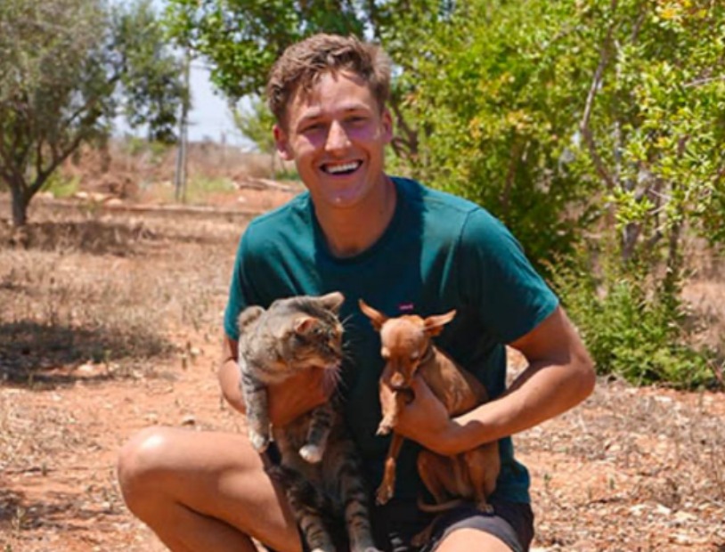 Timothy, investor at Back to Earth, holding two rescued cats in the sanctuary garden