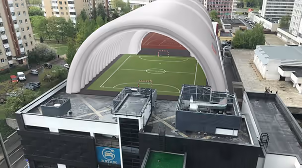 Urban rooftop soccer field with inflatable white dome partially covering the pitch.