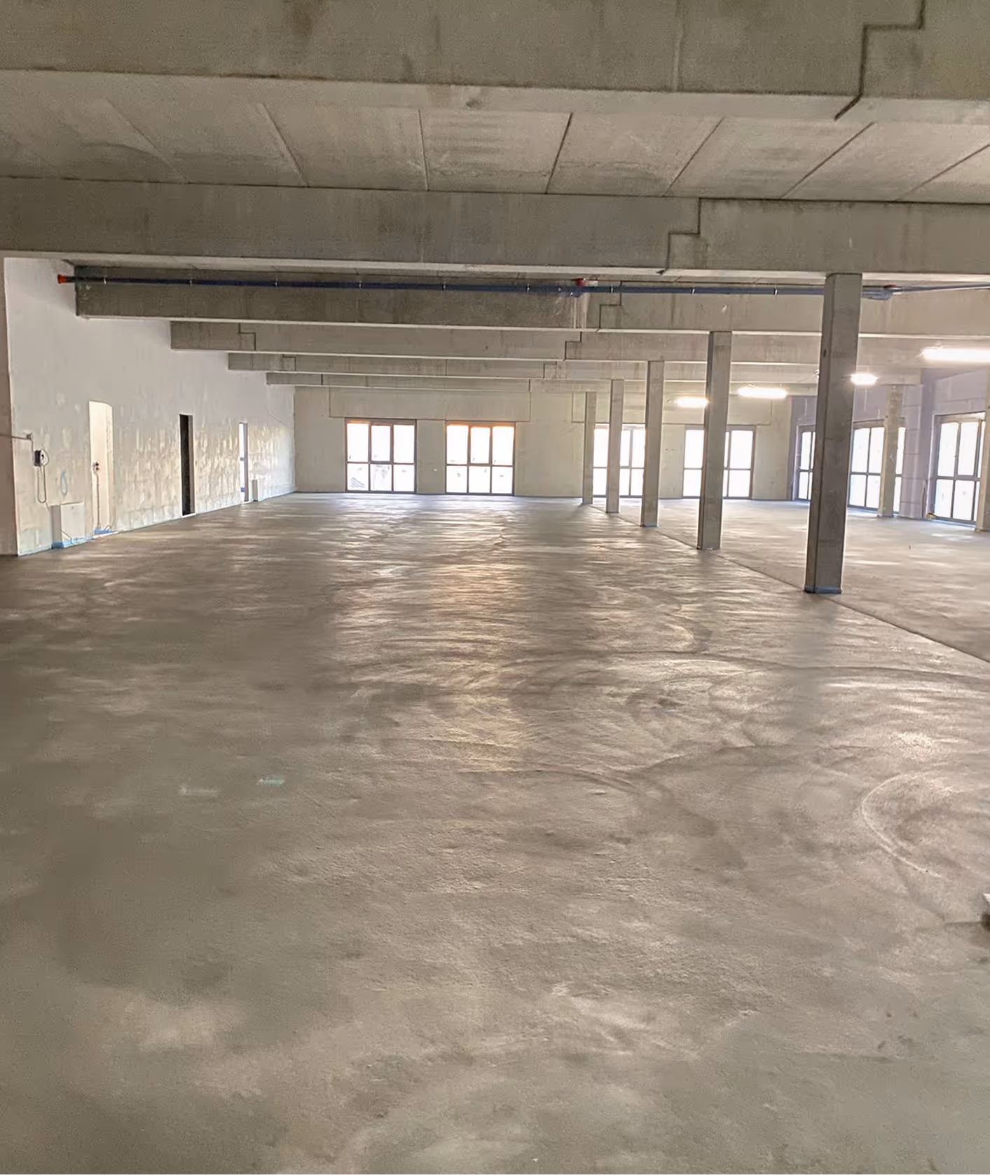 Großflächig verlegter Industrieestrich in moderner Halle mit Betonstützen – AG Estriche Heilbronn