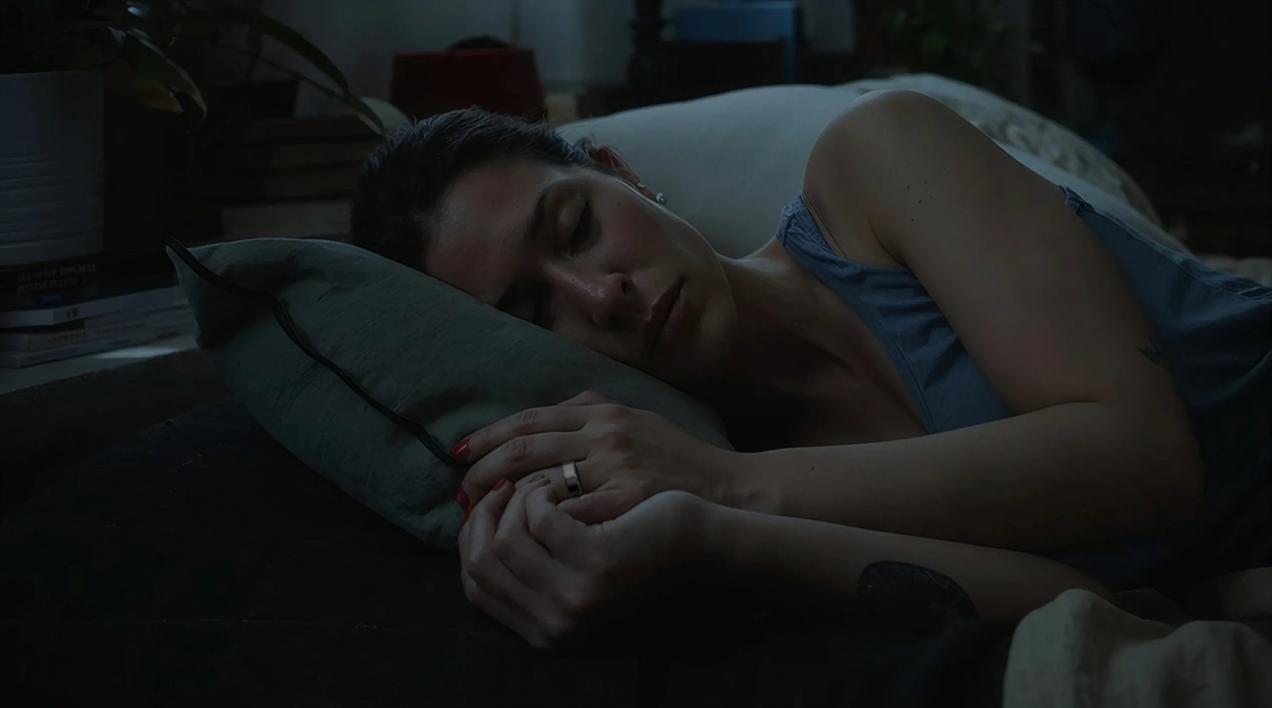 A lady wearing a leep smart ring sleeping deeply in a darkened room.