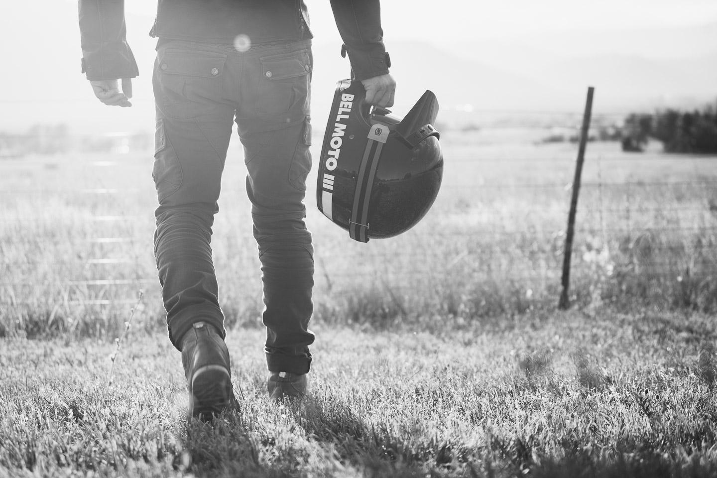 Man holding motorcycle helmet at sunset