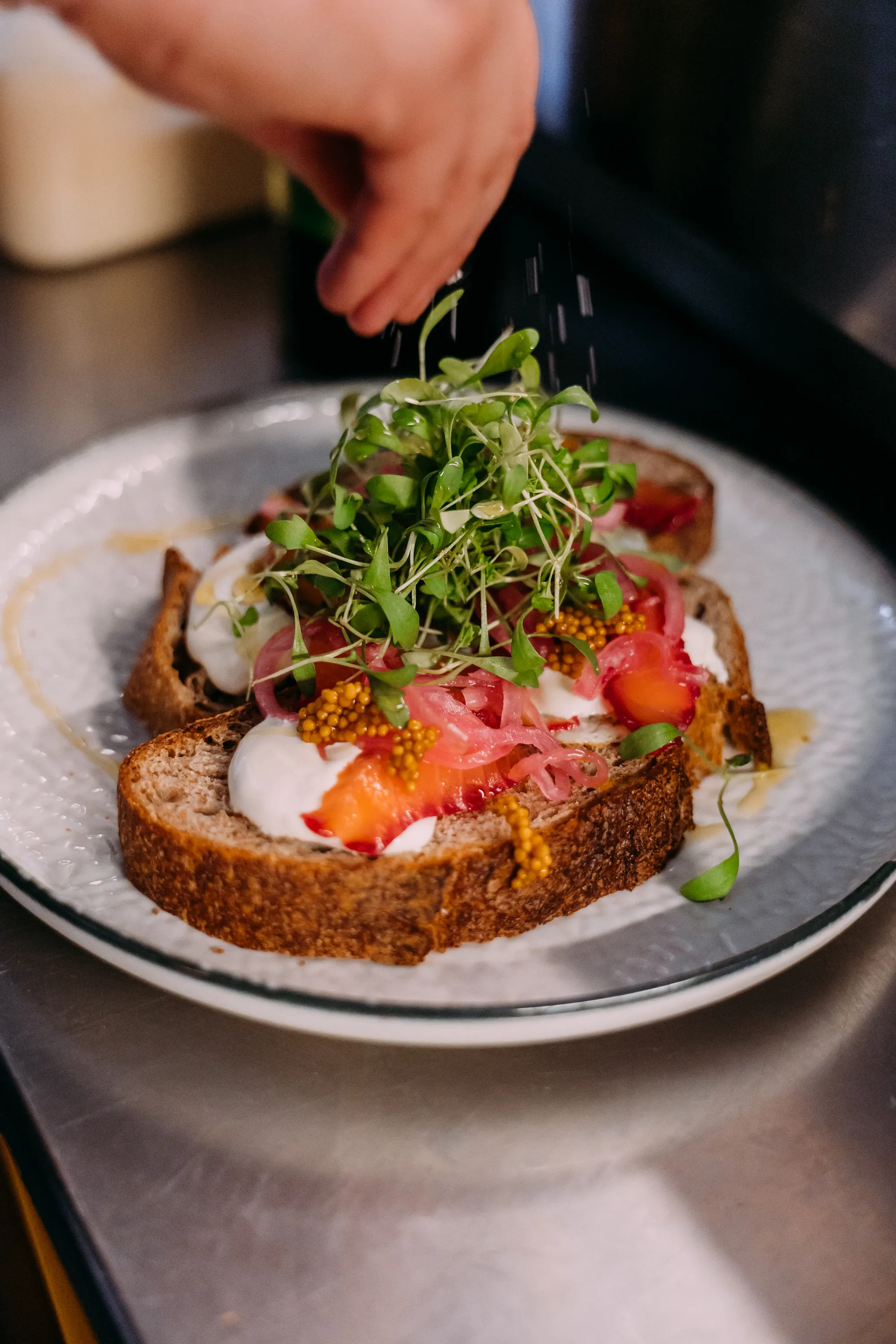 A dish with cheese, salmon, toast and other ingredients being prepared