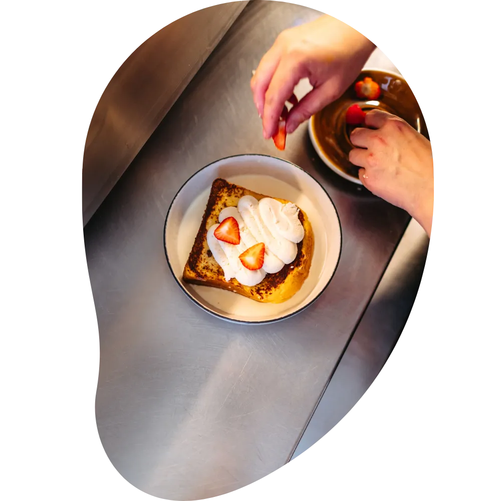A dish with straberies and cream being prepared in the kitchen