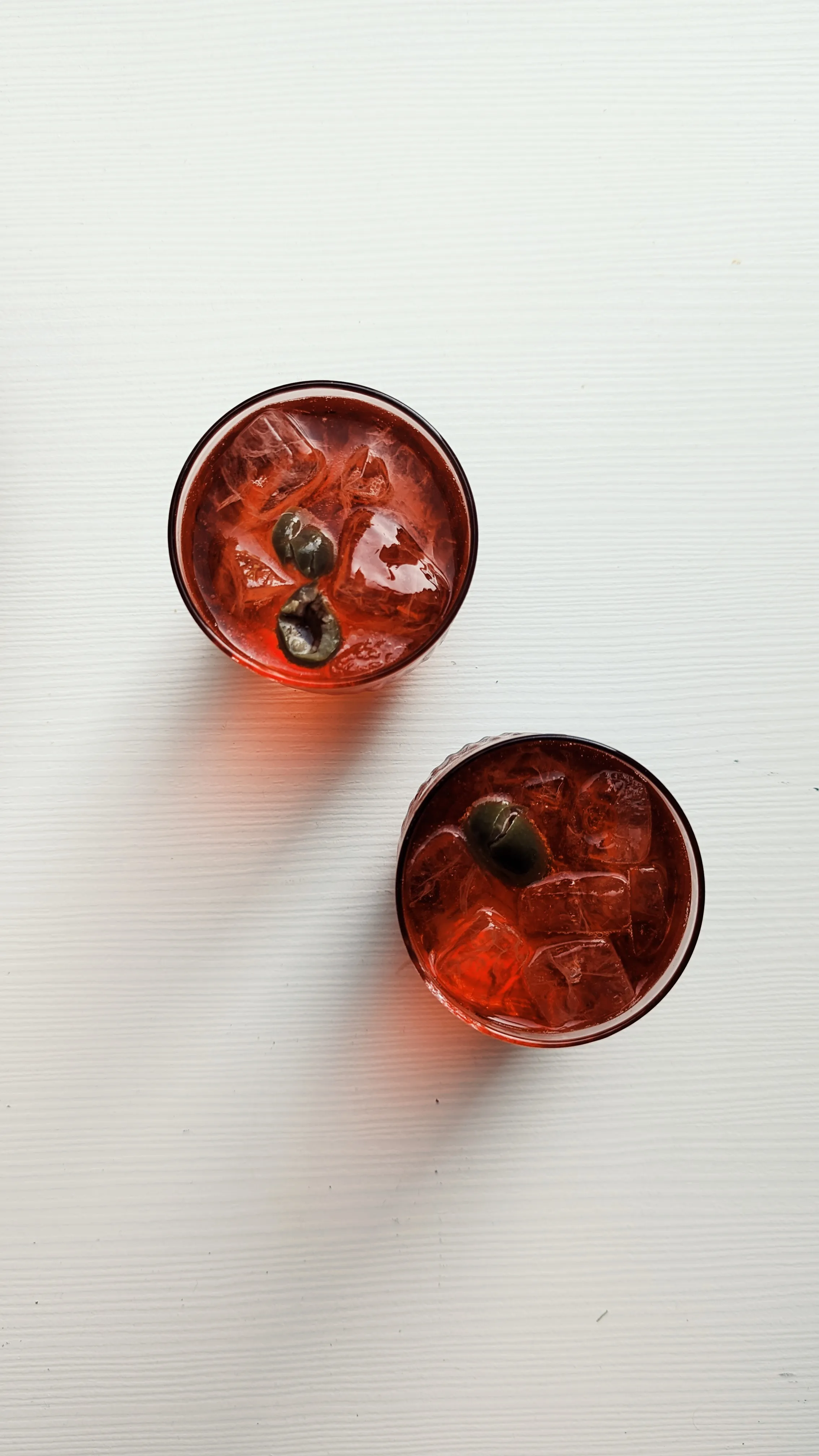 2 red drinks with ice and olives
