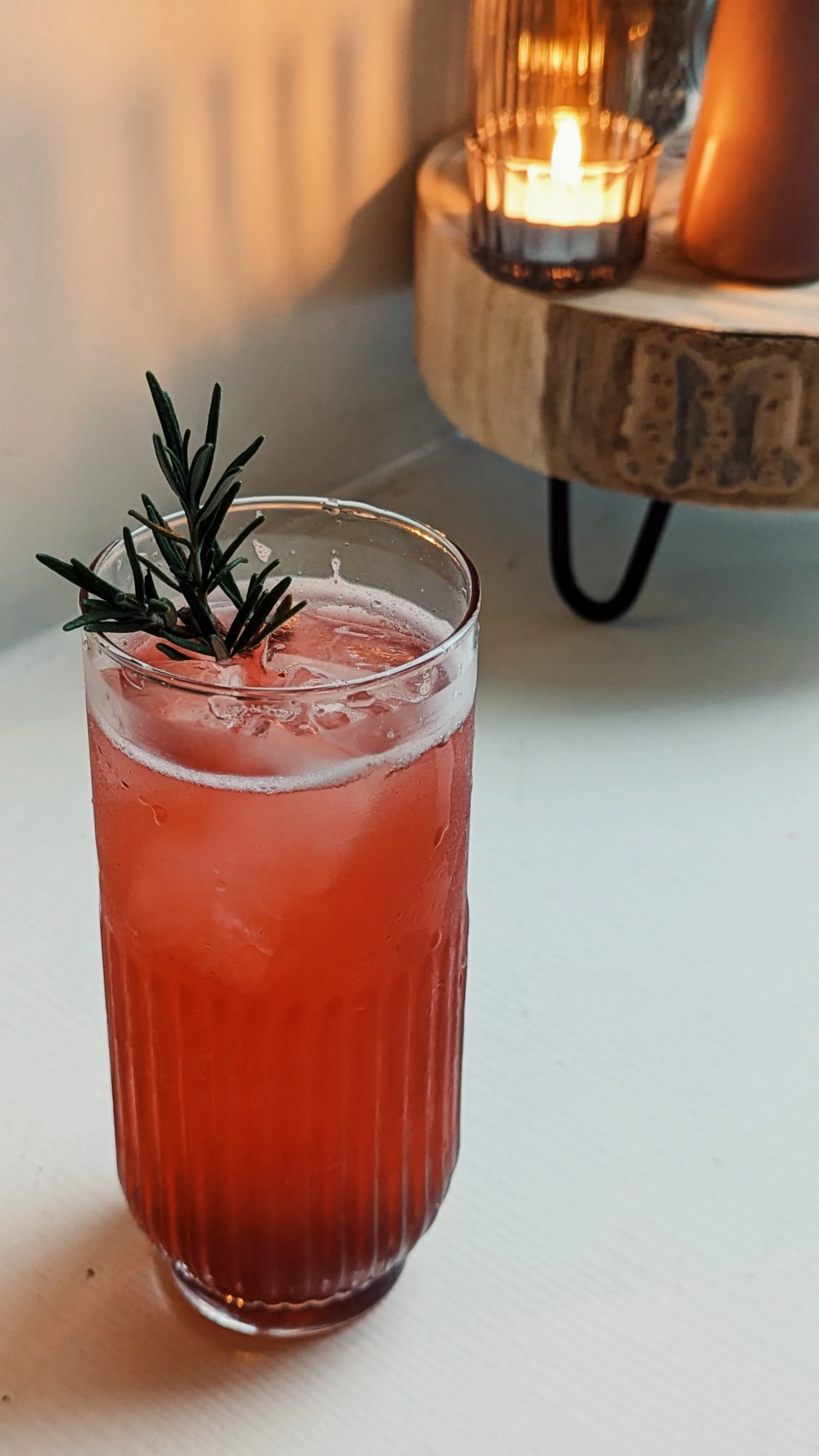 A red drink with rosemary and a cosy candle