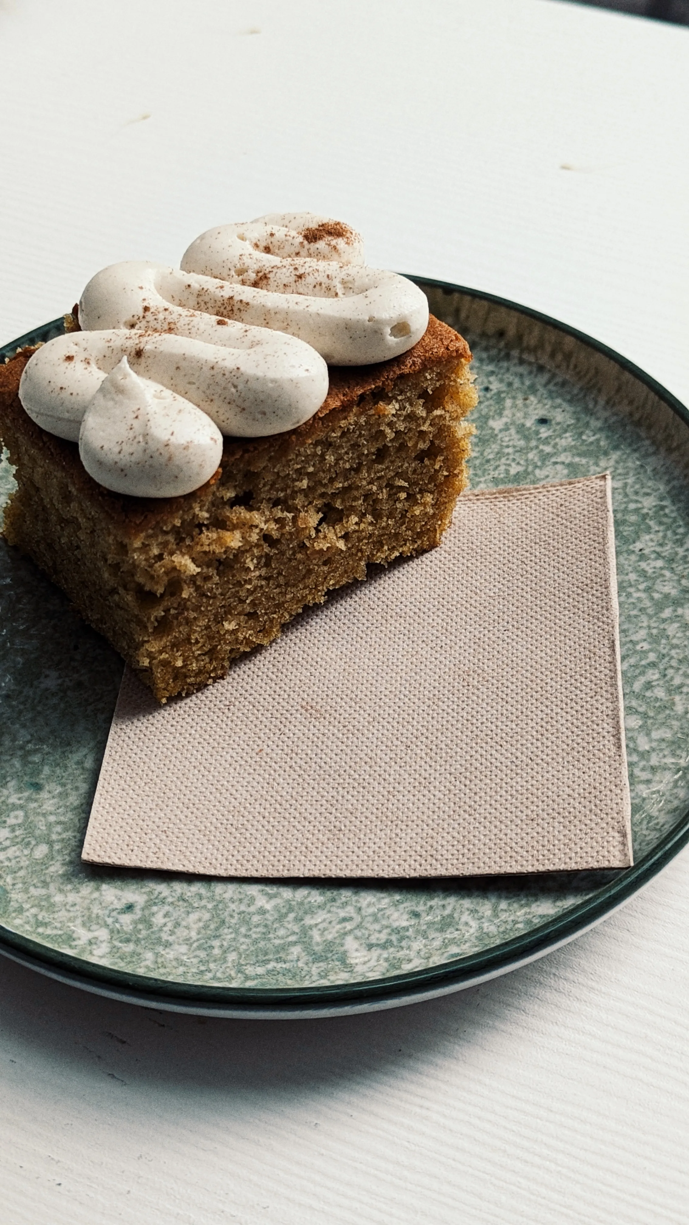 A nicely presented cake with cream on top and a napkin on a plate