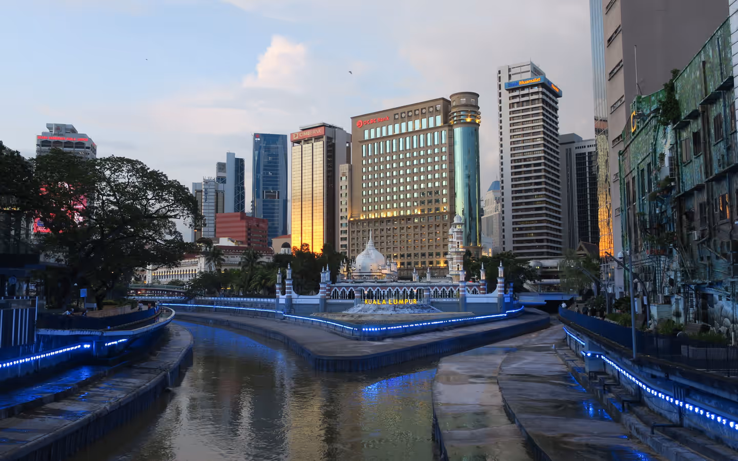 A captivating view of Kuala Lumpur's skyline and river, showcasing modern architecture and evening lights.