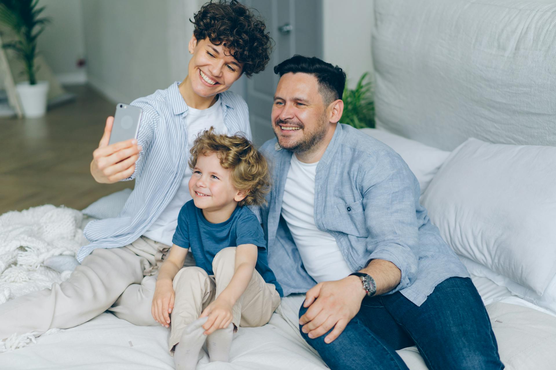 Smiling international family taking a selfie on a bed