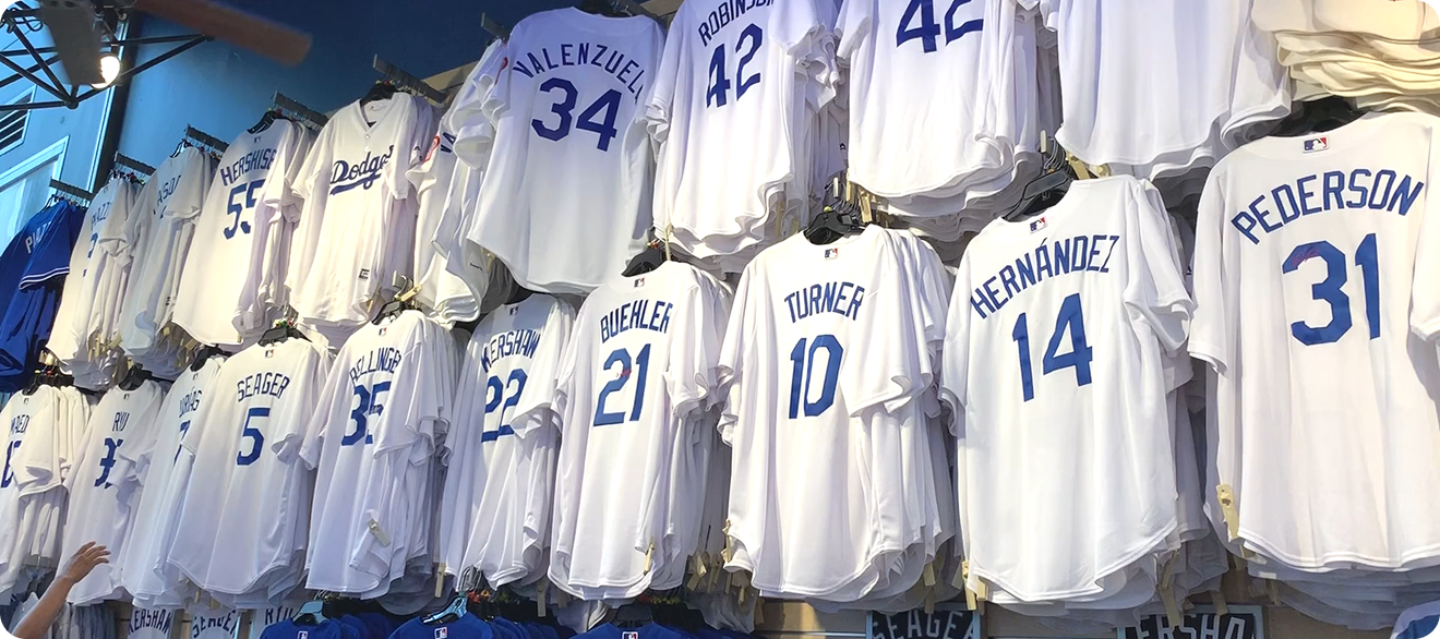 White Los Angeles Dodgers baseball jerseys hanging on display with player names and numbers like Valenzuela 34, Robinson 42, Hernandez 14, and Pederson 31.