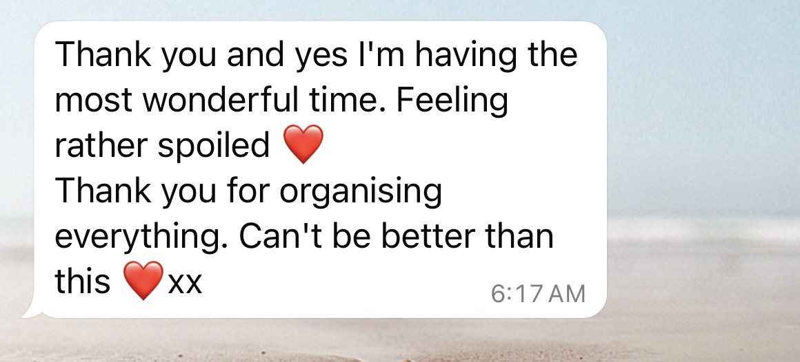 A text message screenshot showing a white message bubble with the text 'Thank you and yes I'm having the most wonderful time. Feeling rather spoiled' followed by a red heart emoji, then 'Thank you for organising everything. Can't be better than this' followed by another red heart emoji and 'xx'