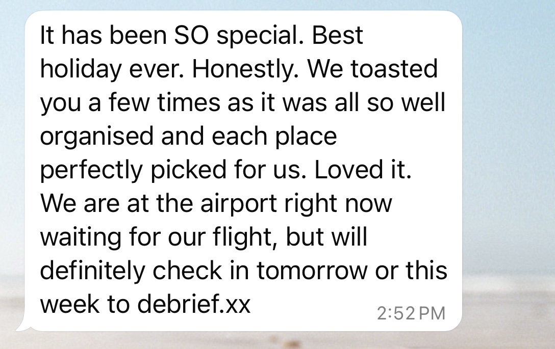 Here's alt text for the image:
"A text message screenshot showing a white message bubble with the text 'It has been SO special. Best holiday ever. Honestly. We toasted you a few times as it was all so well organised and each place perfectly picked for us. Loved it. We are at the airport right now waiting for our flight, but will definitely check in tomorrow or this week to debrief.xx'