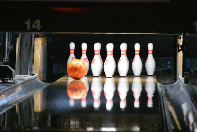 A bowling ball rolling down the lane towards seven pins.
