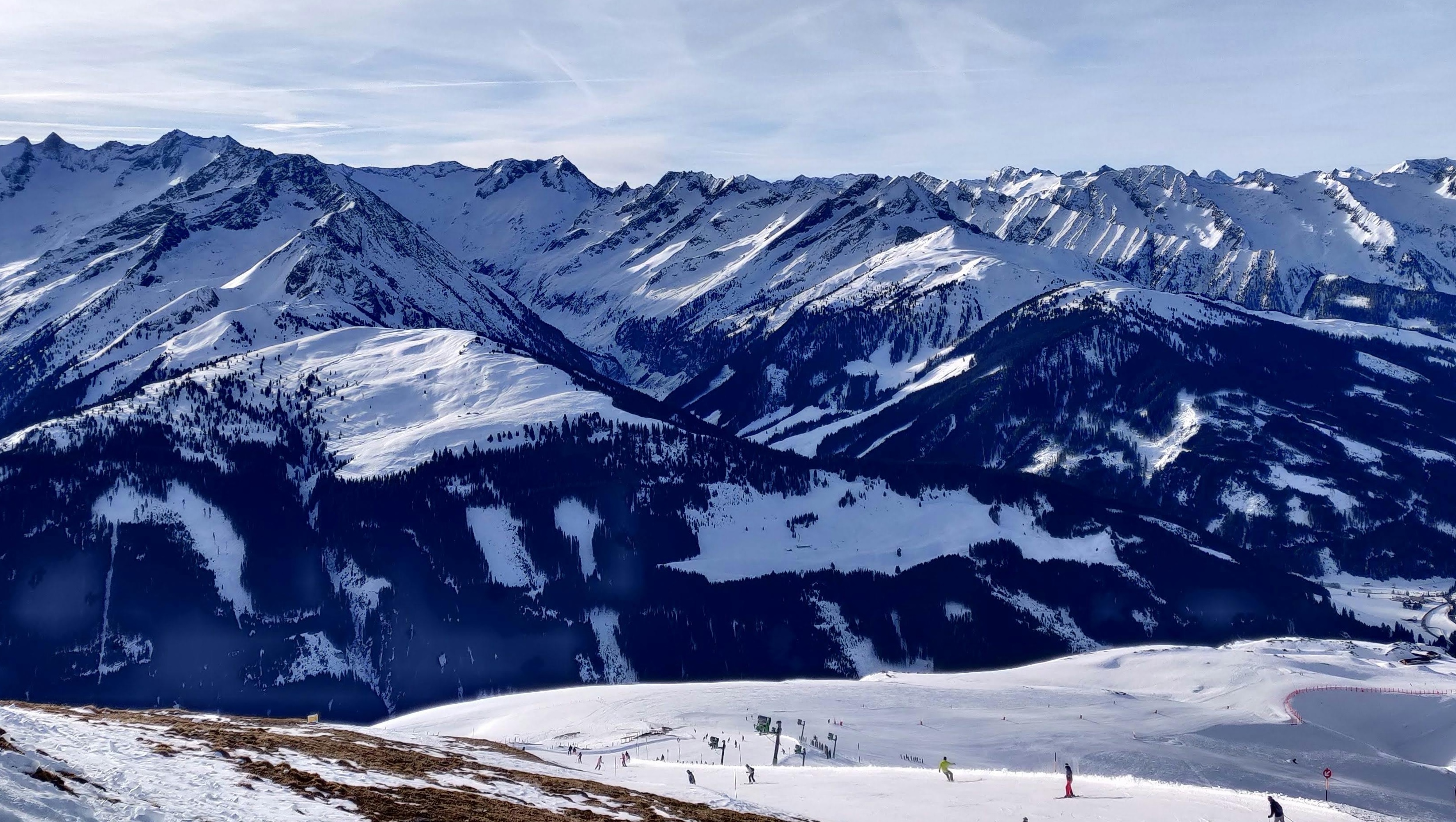 Snow-covered slopes and skiers in St. Anton, Austria, surrounded by dramatic Alpine peaks under a clear winter sky.