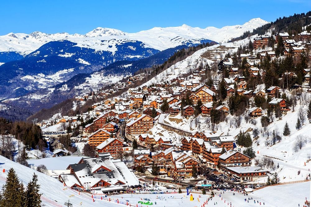 Panoramic view of Meribel ski resort in the French Alps, showing traditional wooden chalets surrounded by snow-covered slopes and mountains.