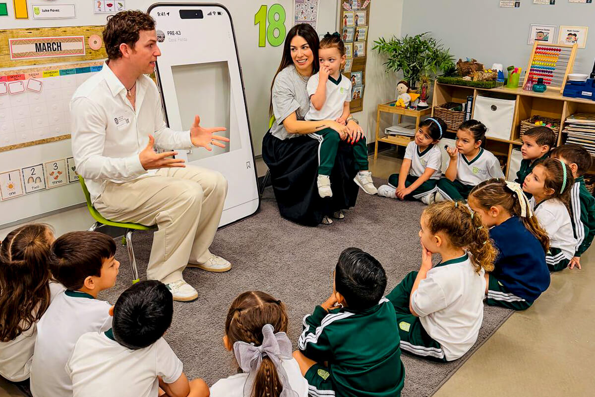 Teacher and assistant with young students sitting in a classroom circle on carpet during group activity.