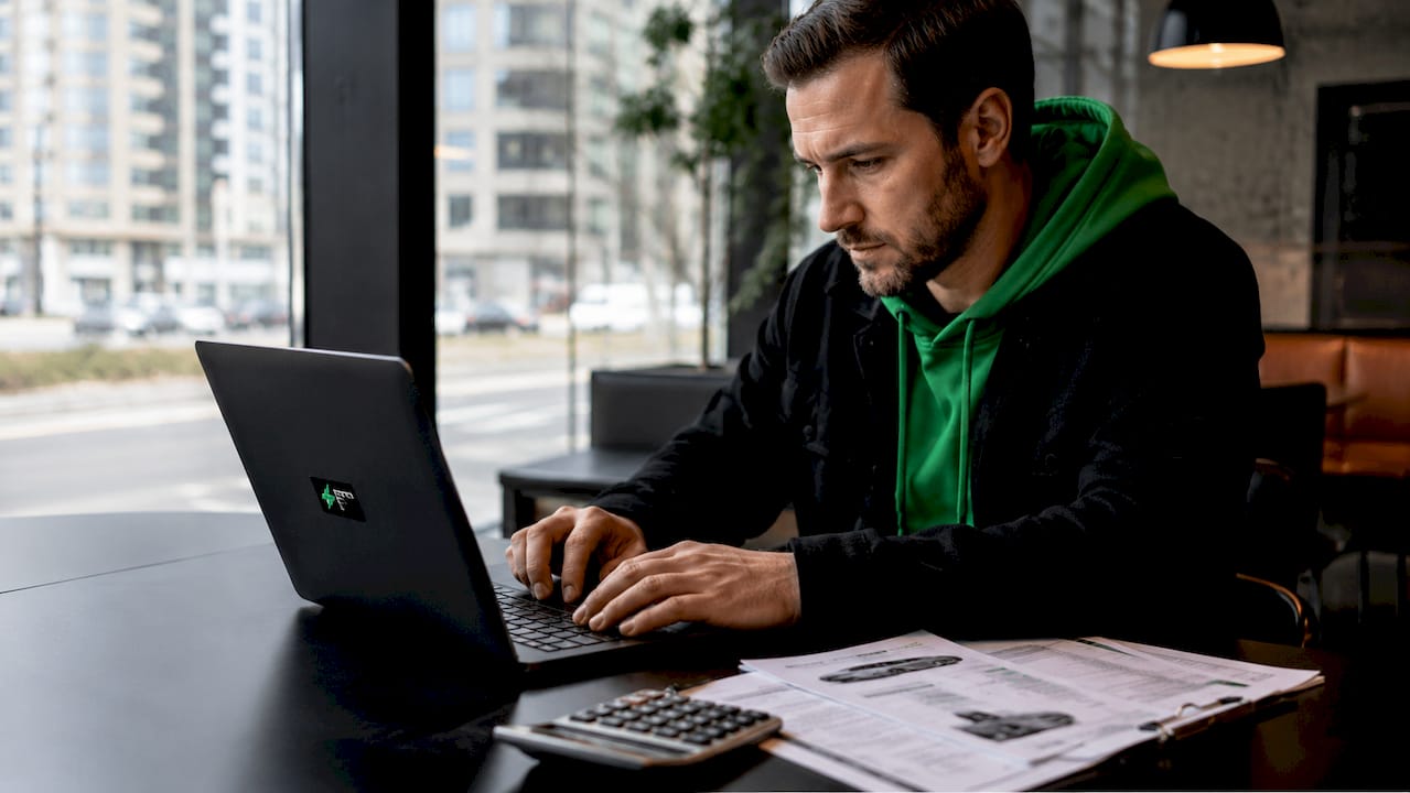 Man using laptop and calculator in home office