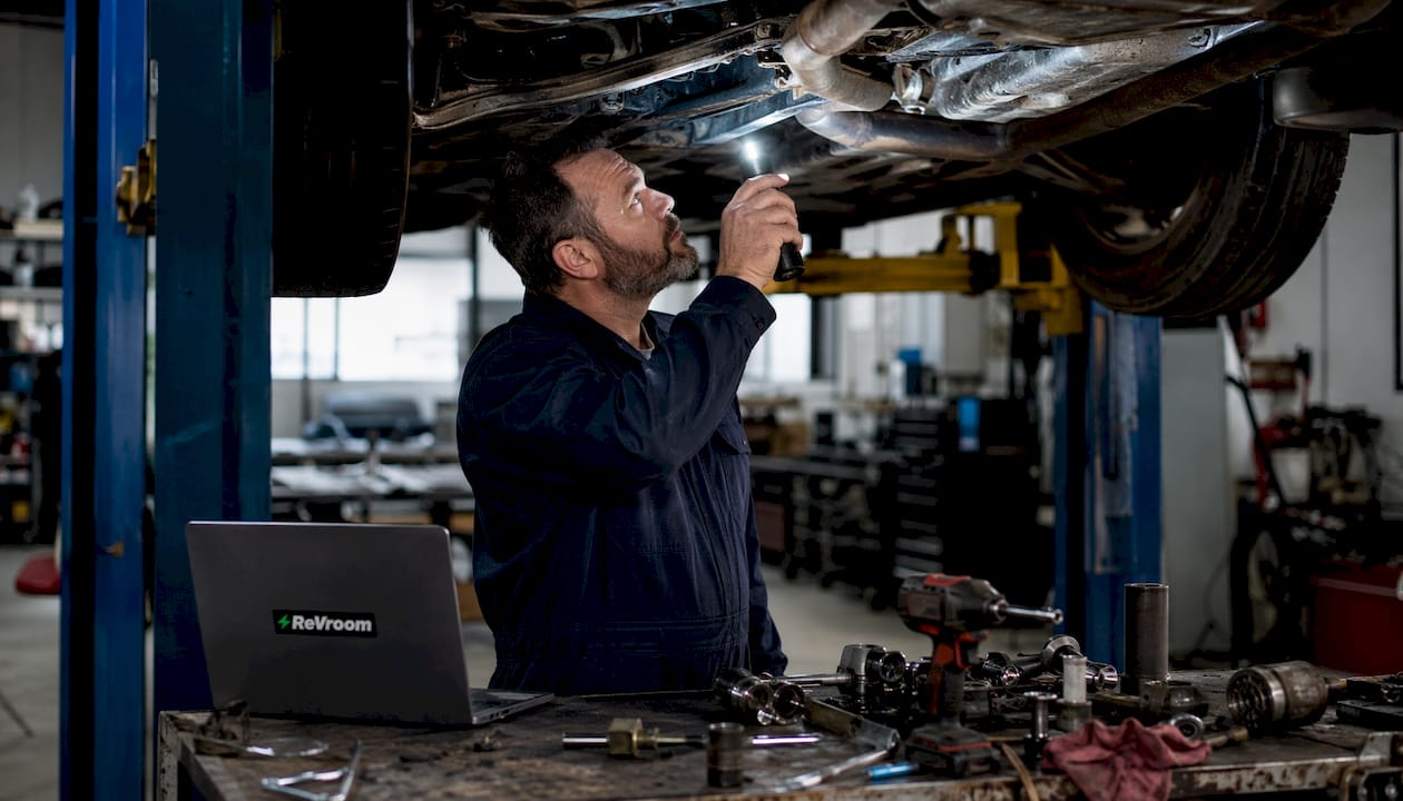Mechanic inspecting rebuilt car undercarriage