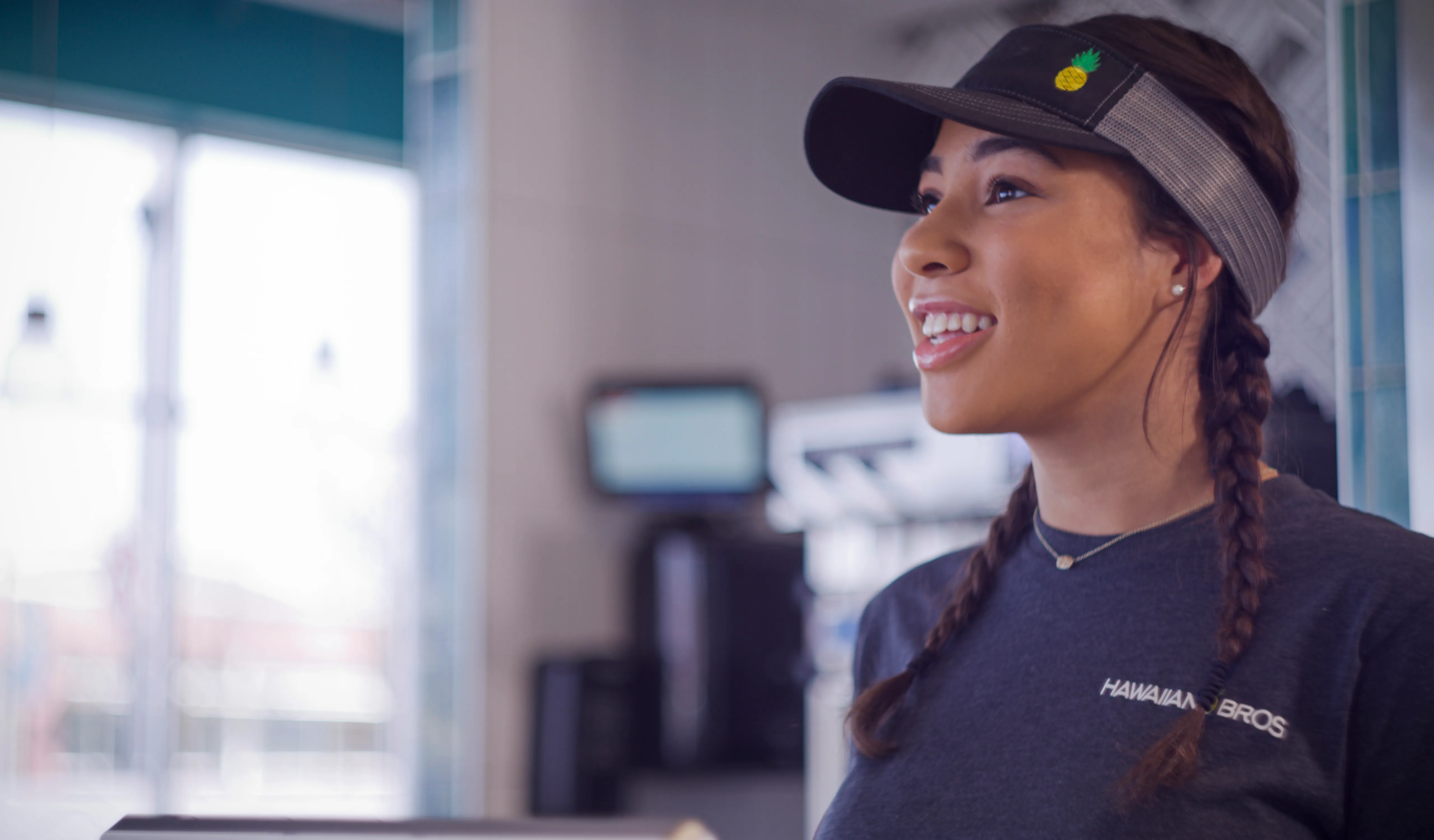 A smiling Hawaiian Bros employee taking a customer's order.