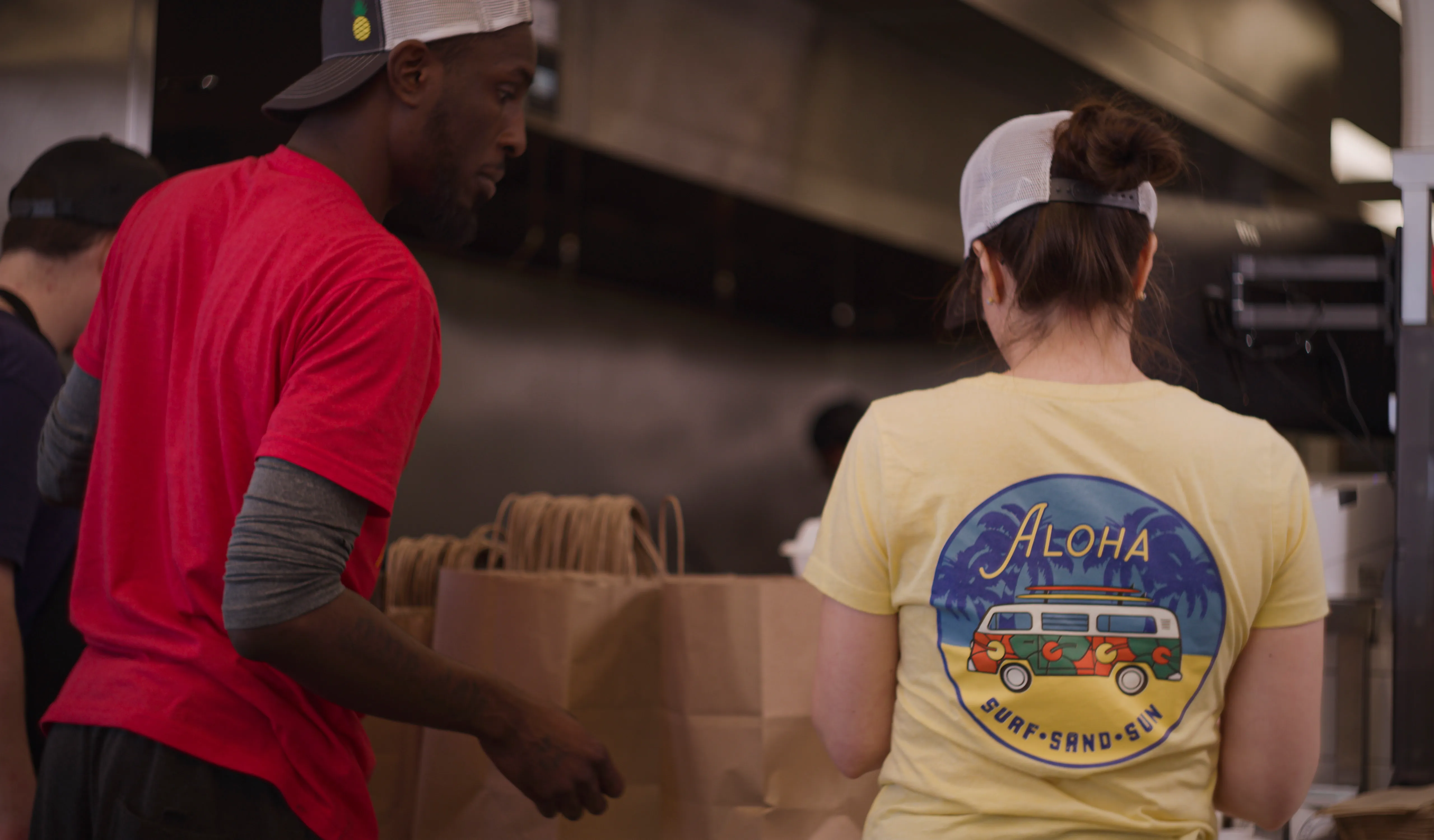 Two Hawaiian Bros employees packing orders in the kitchen.