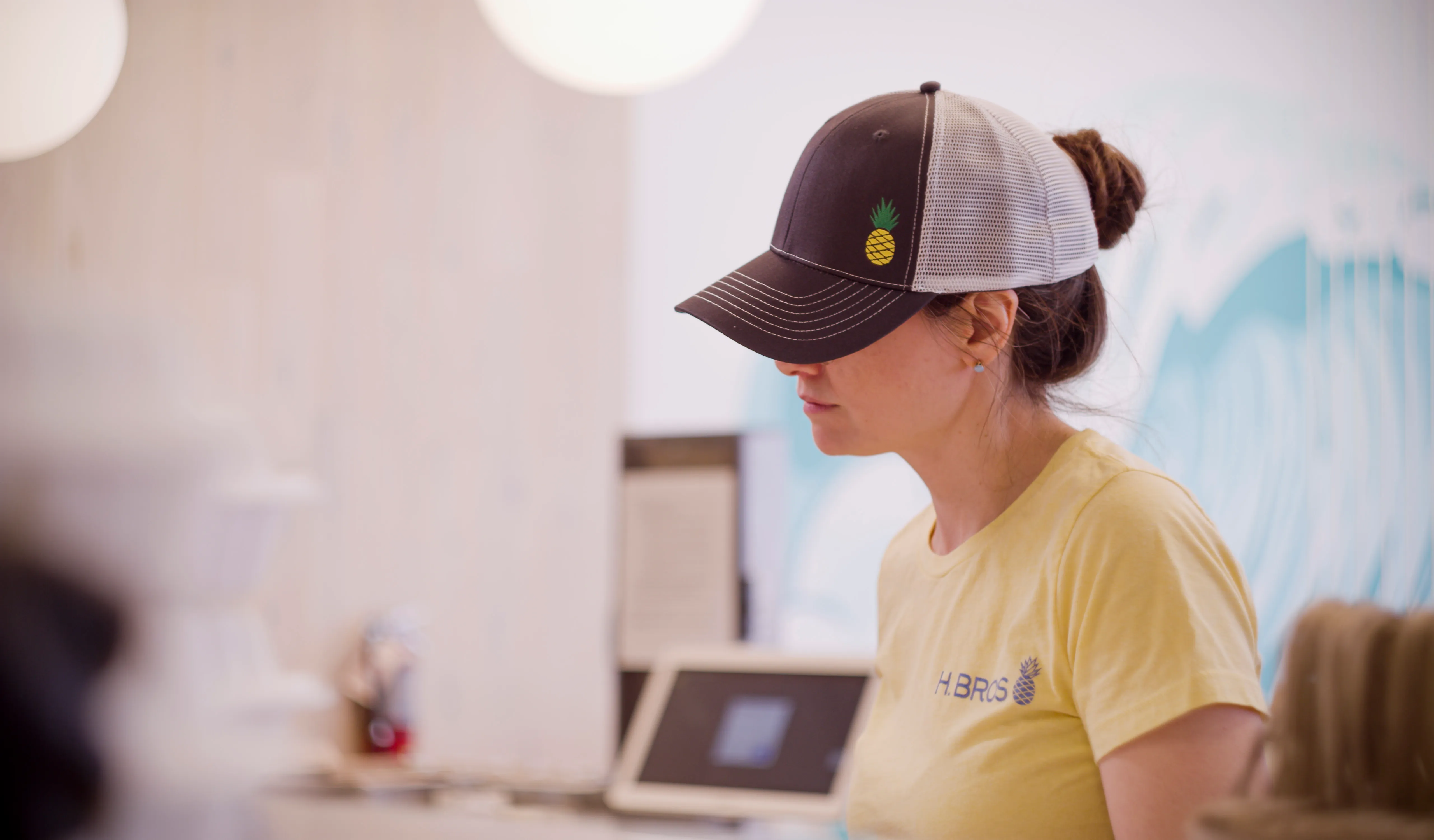 An employee with a Hawaiian Bros hat and yellow shirt at work.