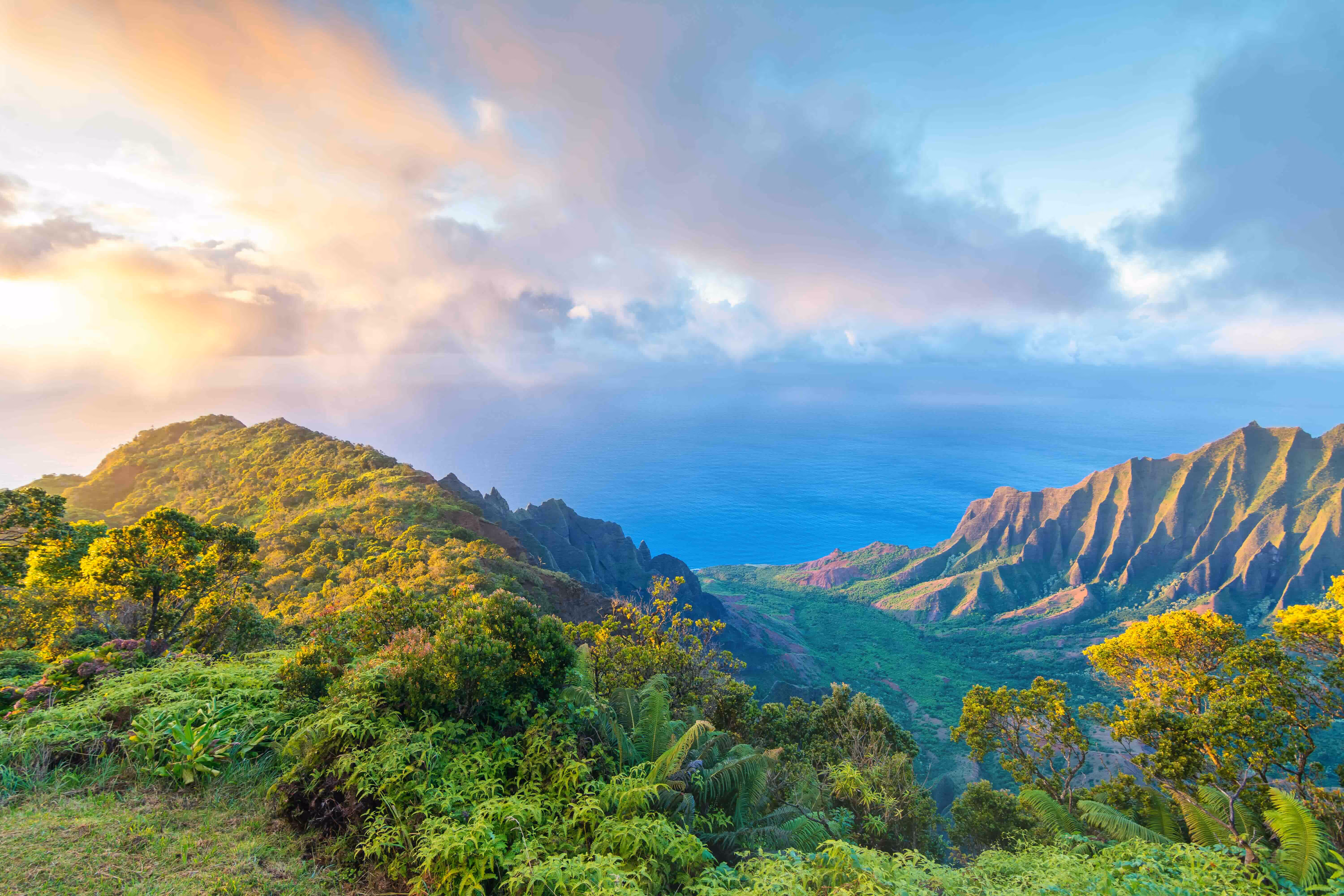 The green Hawaiian mountains with the sun shining through the clouds. 