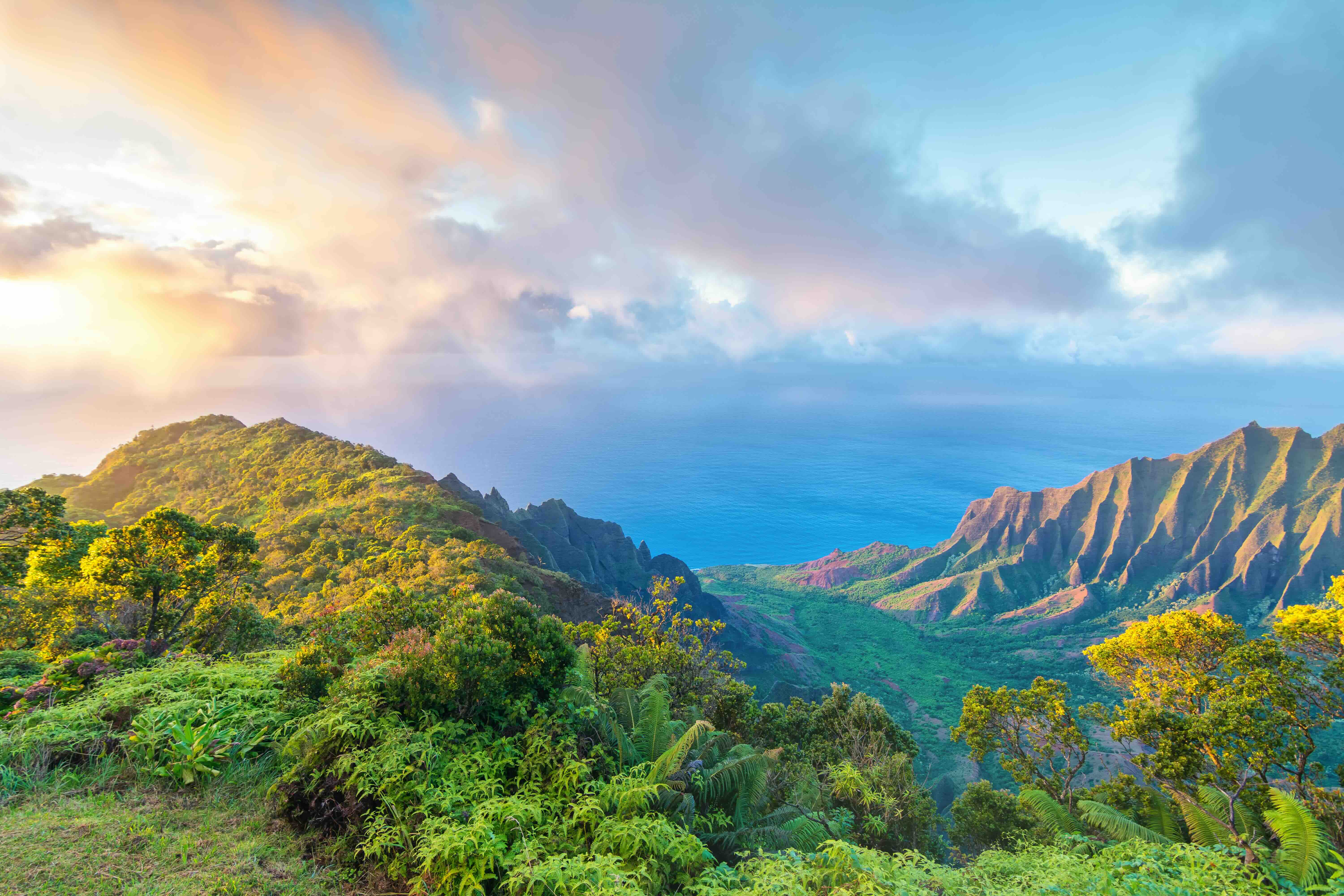 The green Hawaiian mountains with the sun shining through the clouds.