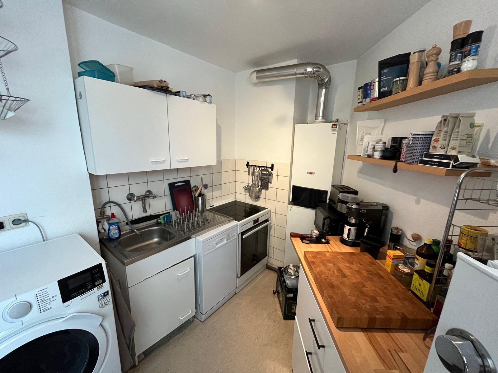 Einbauküche mit Herd, Backofen, Spülmaschine und Arbeitsplatte aus Holz in der Wohnung in Aachen